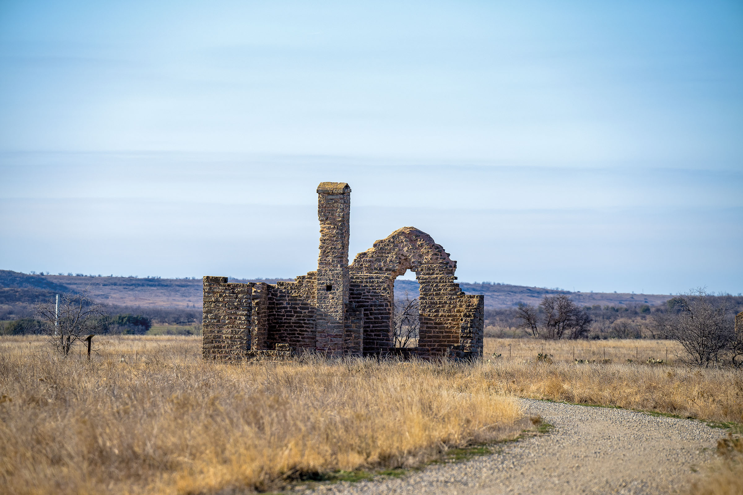A stone structure in a grassy field under grey-blue sky