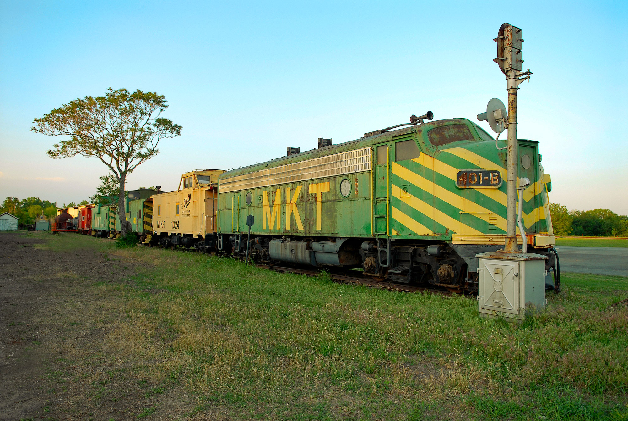 An old, green locomotive with yellow stripes sits on a track