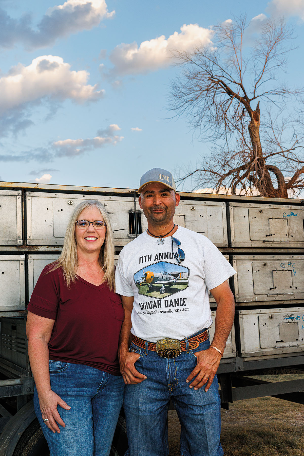 Two people stand in front of a wall of plastic nesting boxes under blue sky