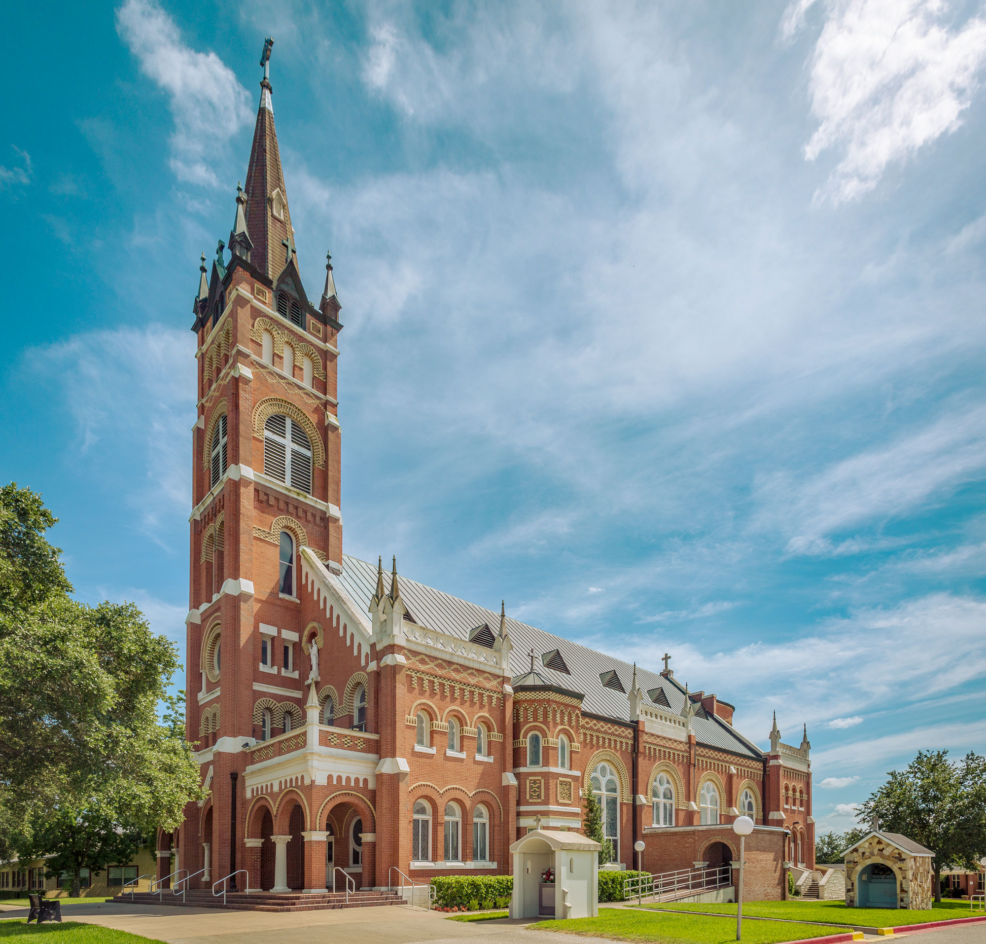 An ornate, large red brick church stands tall against a blue sky