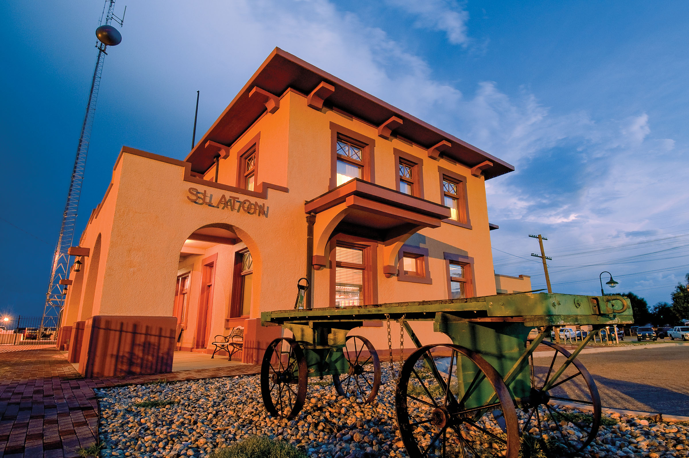 The exterior of a golden-yellow hotel with dark wood trim. An old fashioned wagon is parked in front.