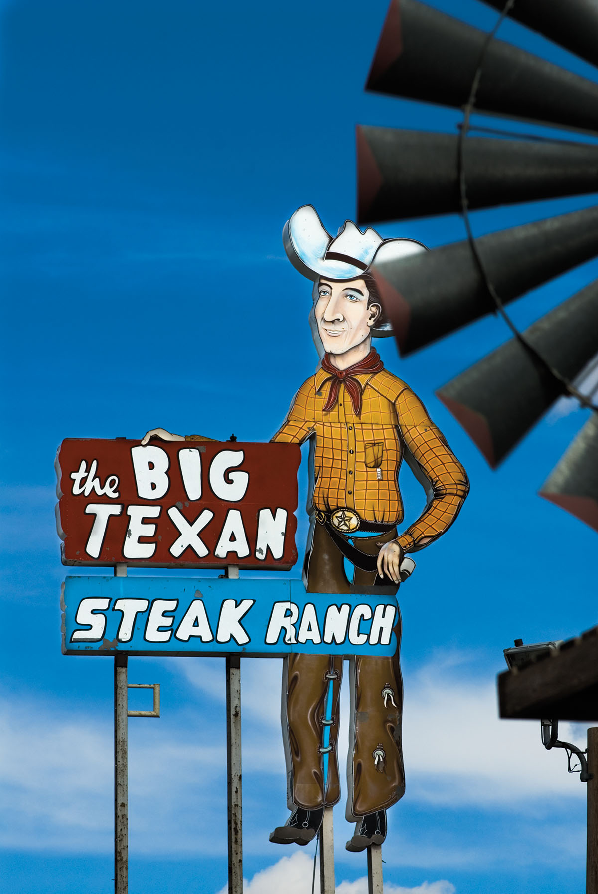 Photo of a large sign with a cowboy next to it that reads "The Big Texan Steak Ranch"