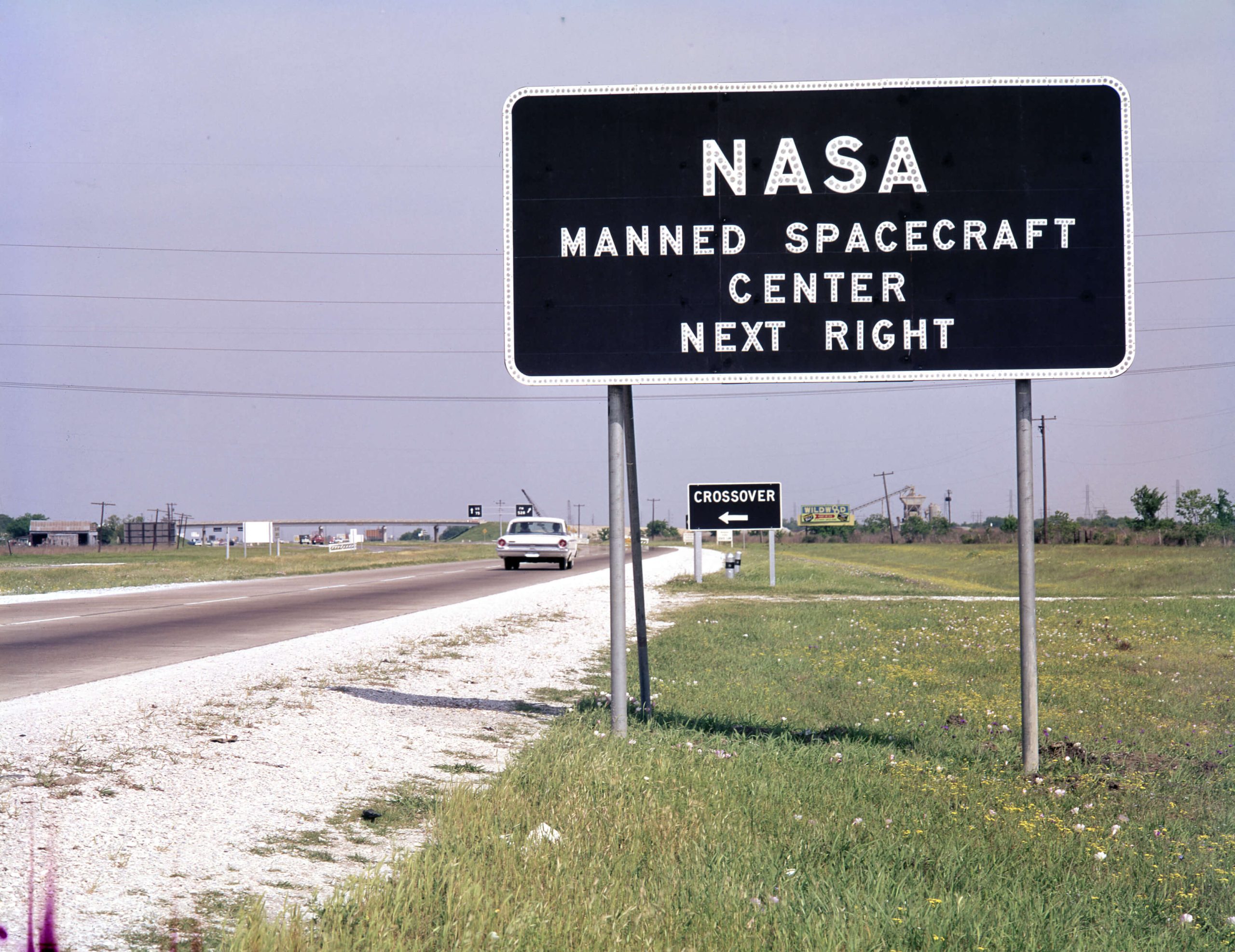 A roadside sign that reads NASA Manned Spacecraft Center Next Right.