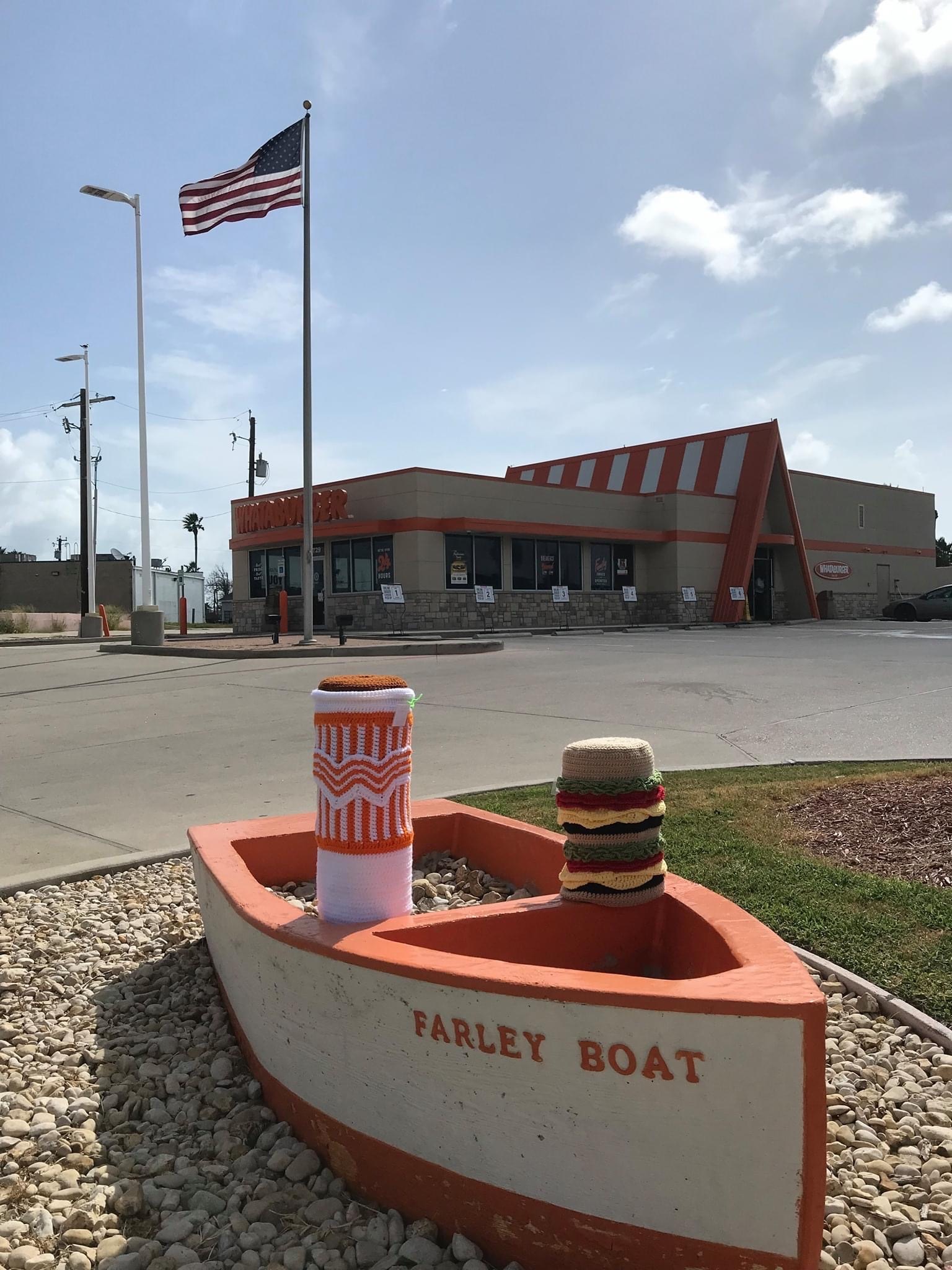 A crocheted Wataburger burger and drink coverings outside of a Whataburger in Port Aransas.