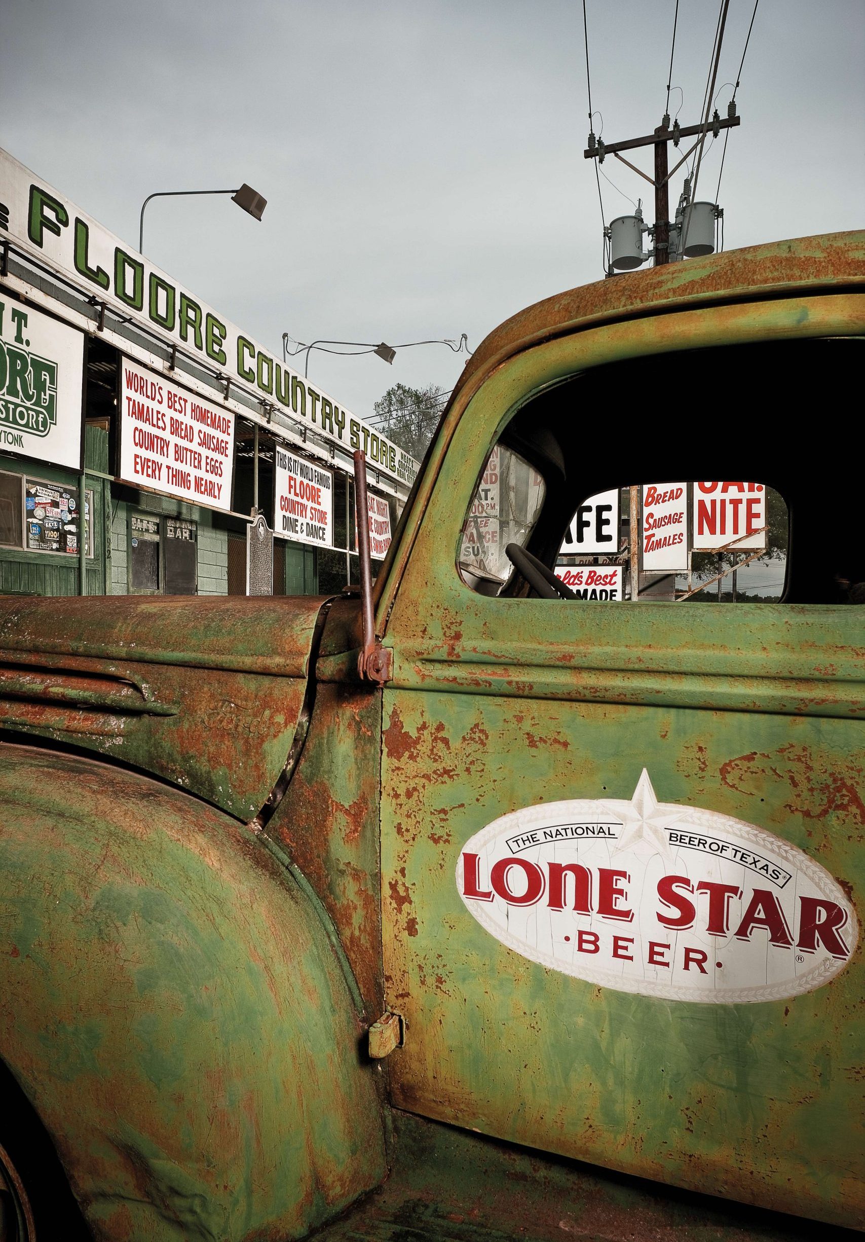 A green vintage and rusted truck with a label on its side that reads "Lone Star Beer"