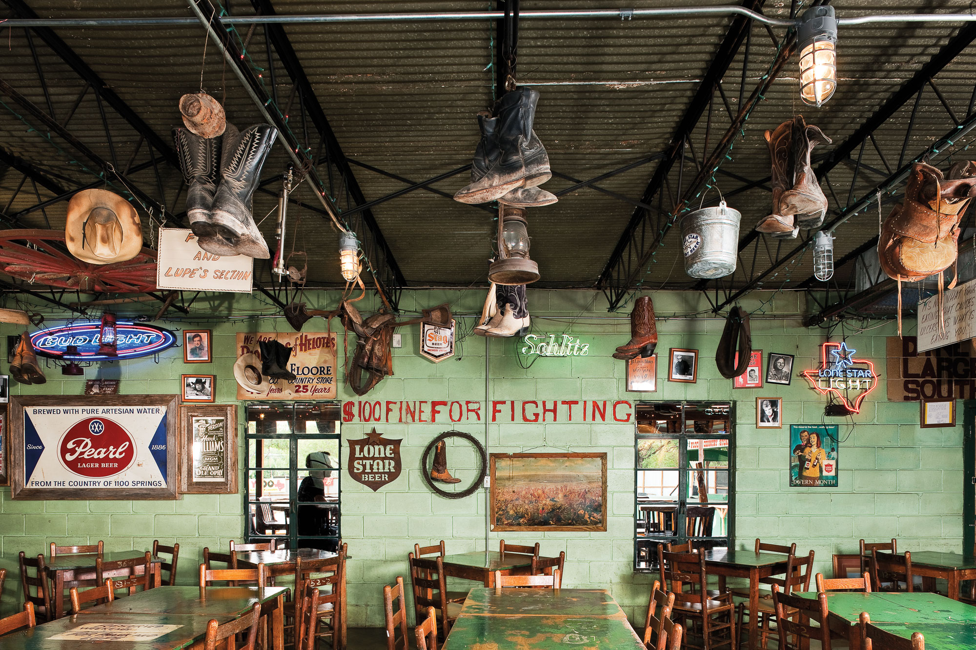 Boots and buckets hang from the ceiling of a green rustic restaurant