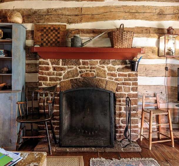 A stone fireplace in an old cottage with wooden beams