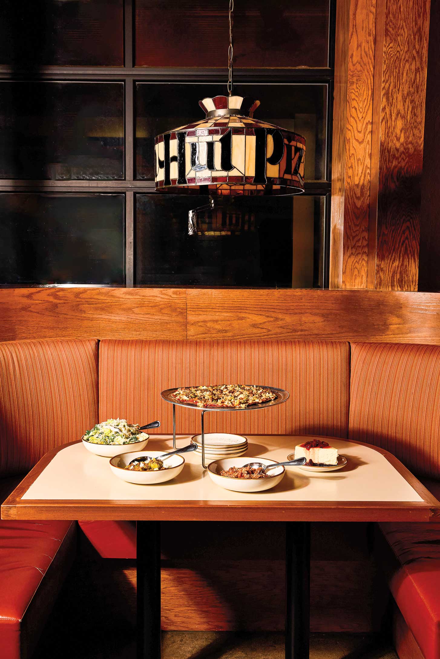 A stain-glass lamp that says "Pizza Hut" hangs above a table.