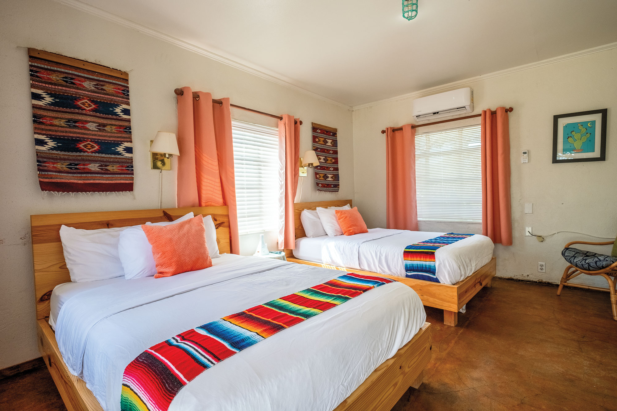 Two beds inside a room with brightly colored linens and curtains