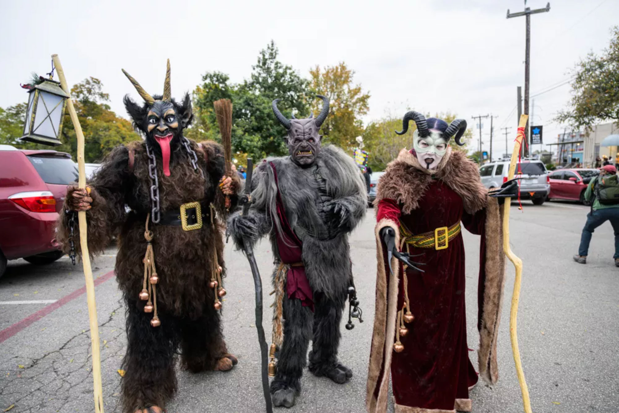 Three people in devilish costumes at a parade.