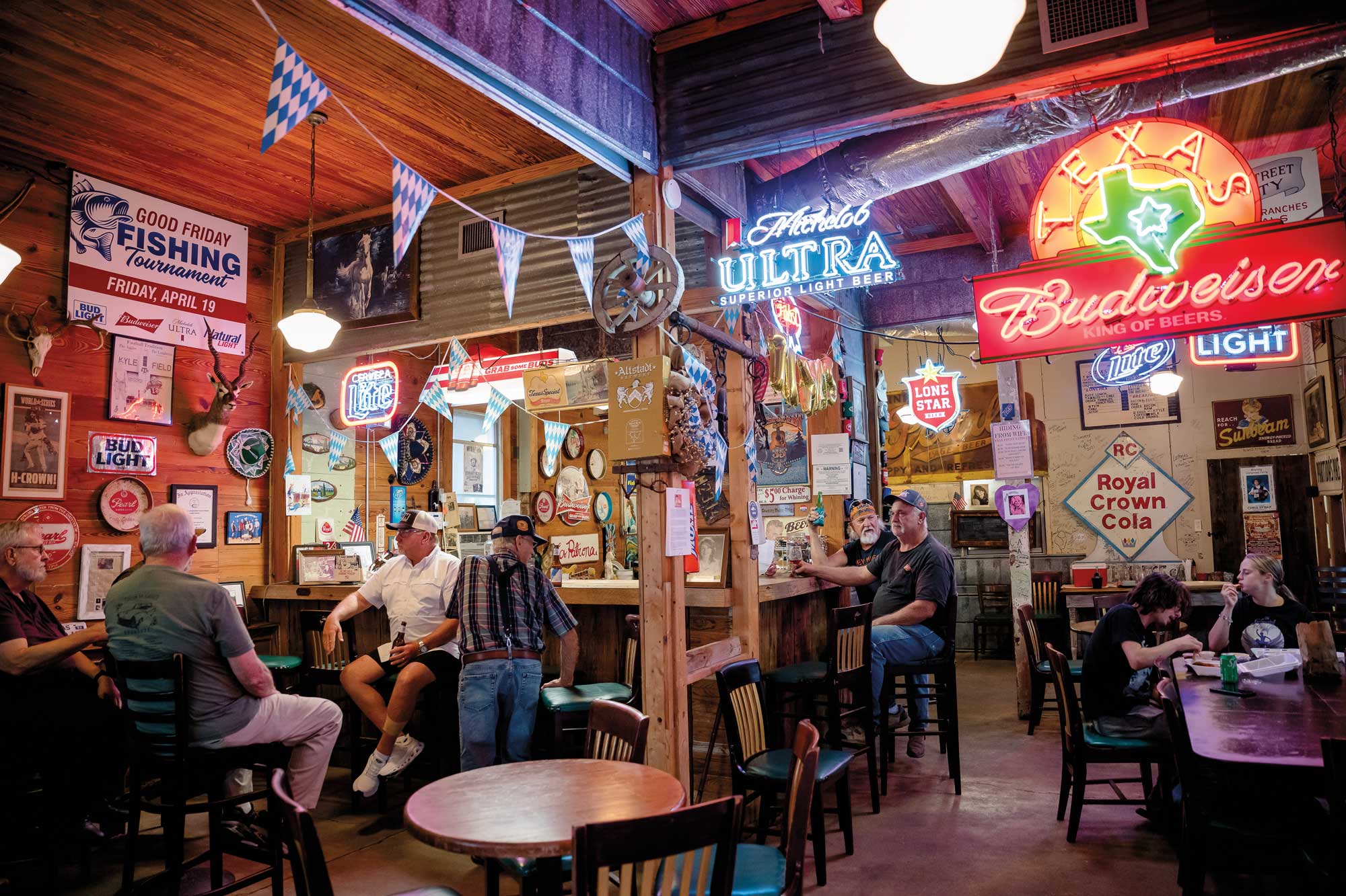 People eating and drinking beneath neon signs in a bar