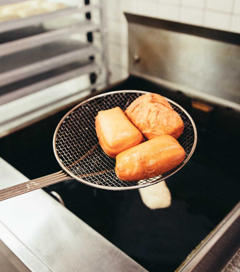 Beignets lifted out of a fryer