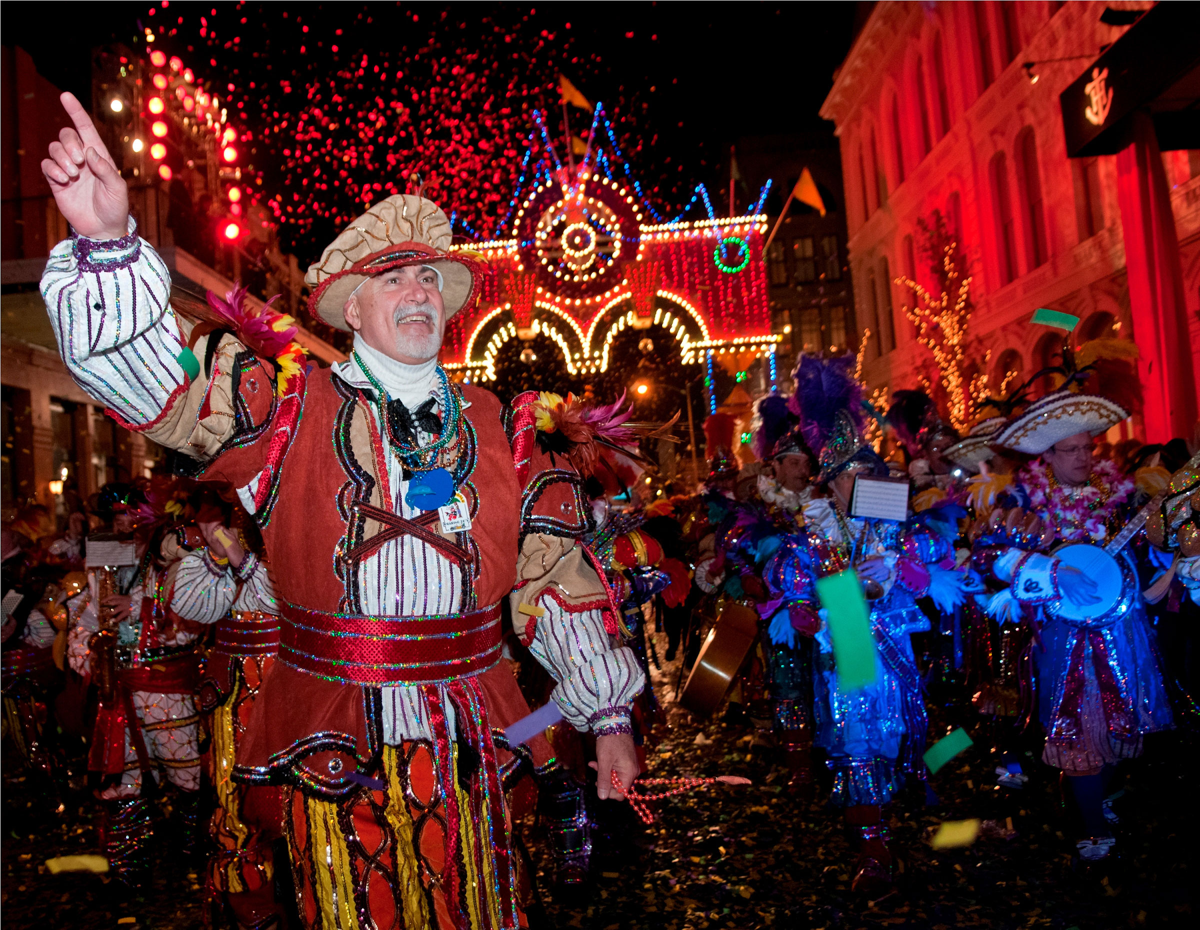 A man dressed up in carnival garb celebrates among a festival crowd