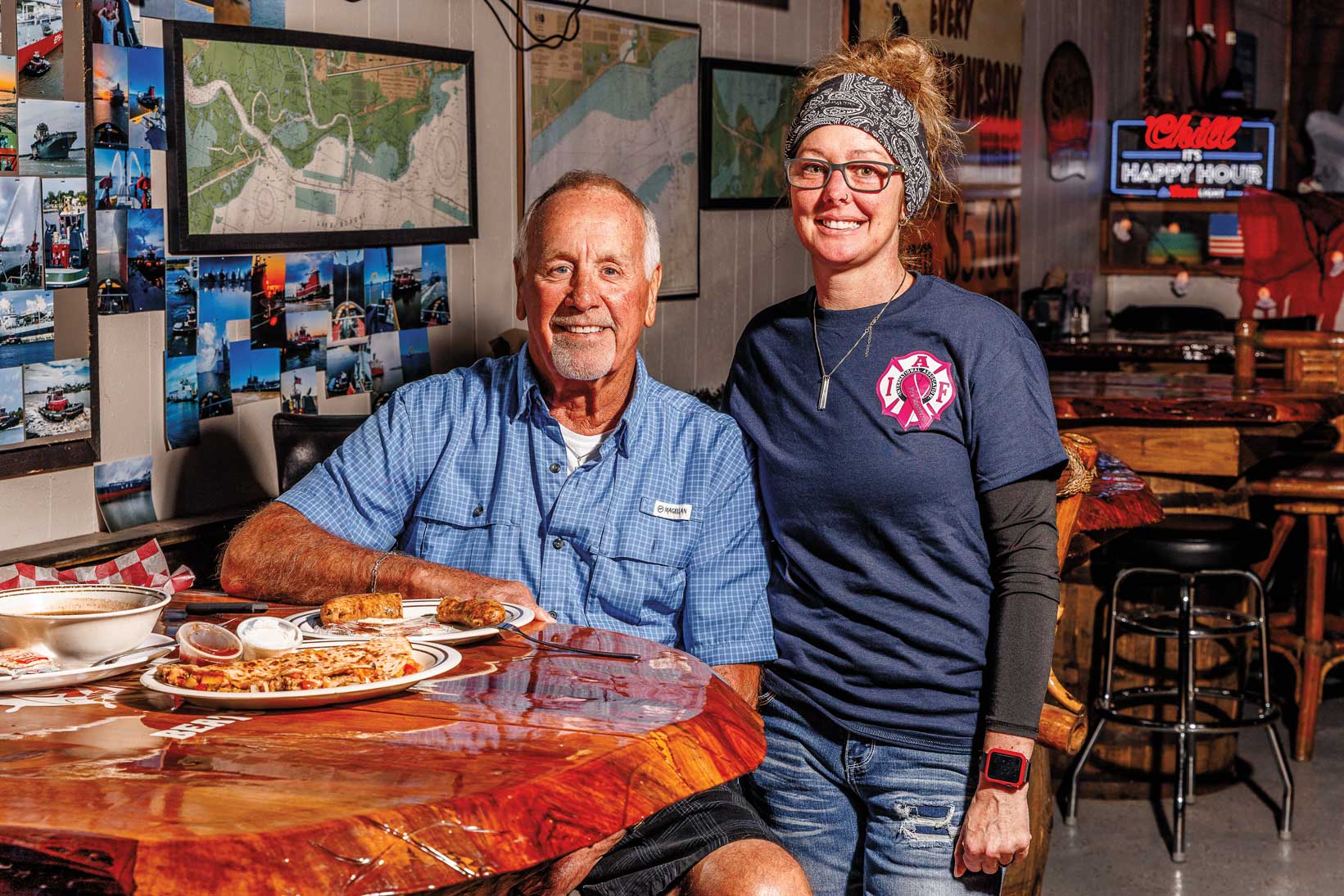 A man and woman pose next to plate of sausage