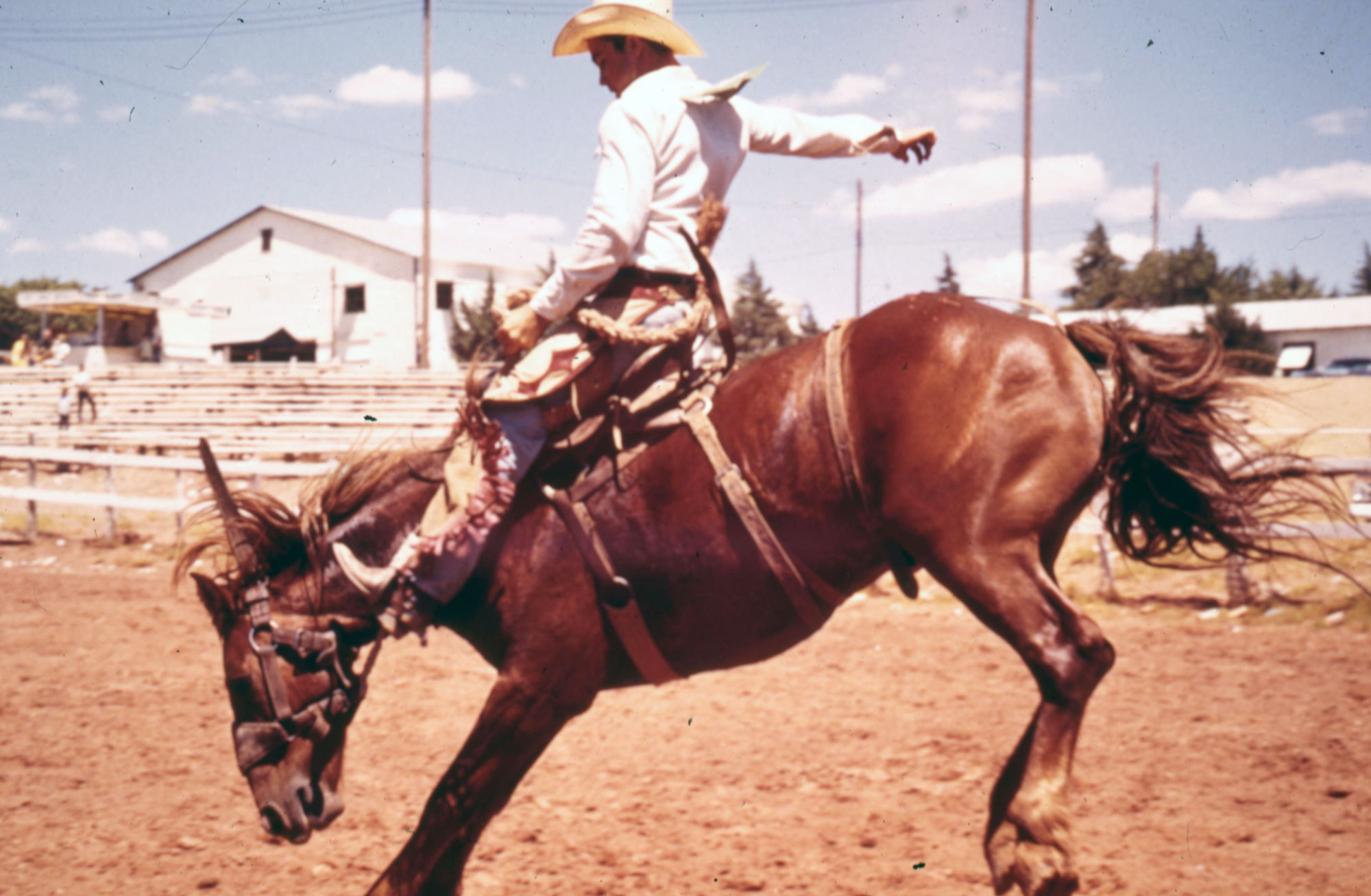 A cowboy in rodeo clothing riding a horse