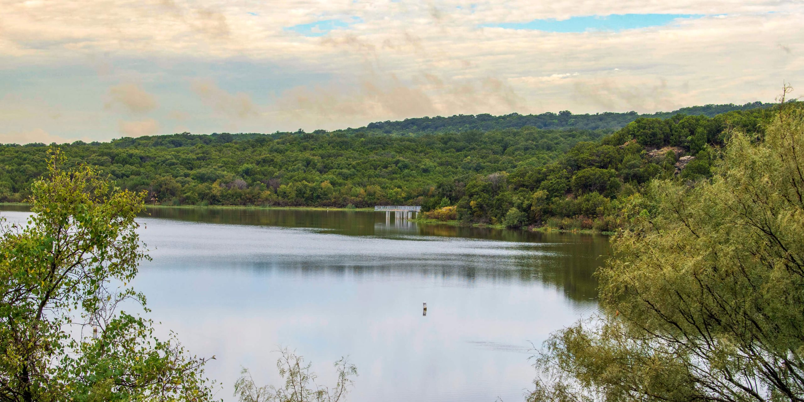 A landscape shot of a lake backdropped by a lush, green hill