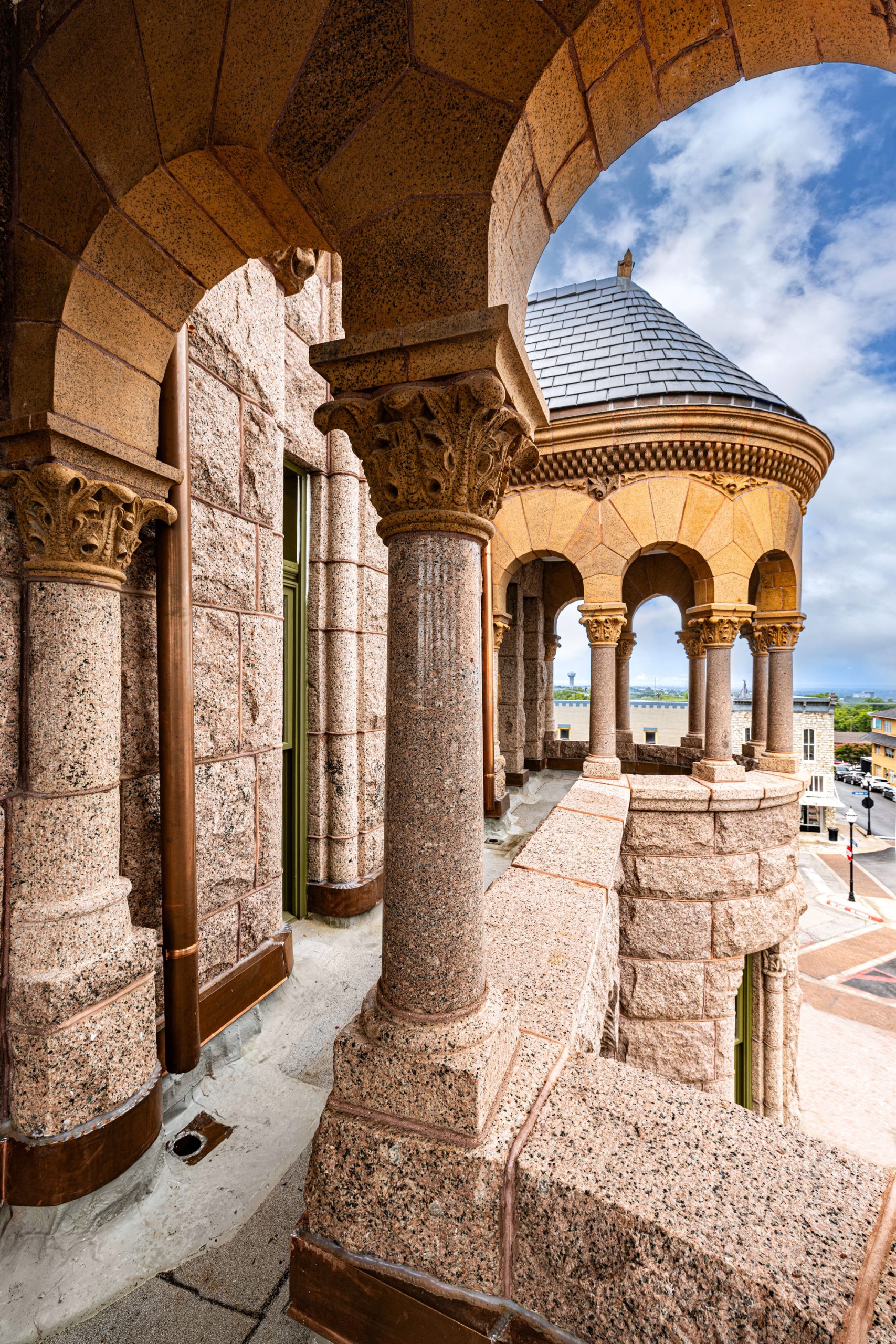 The view of a limstone courthouse peering through the arches of the upper balcony