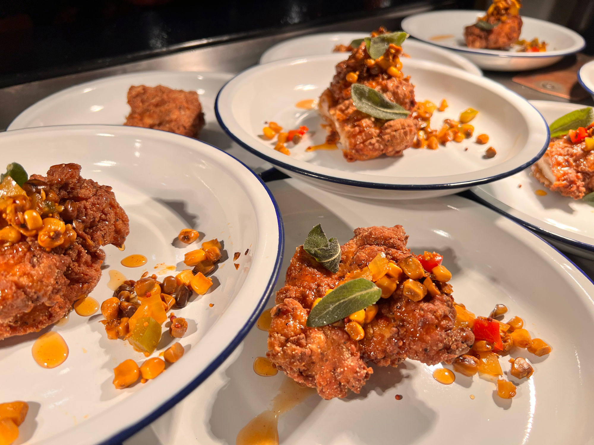Plates of fried chicken garnished with corn and sage.