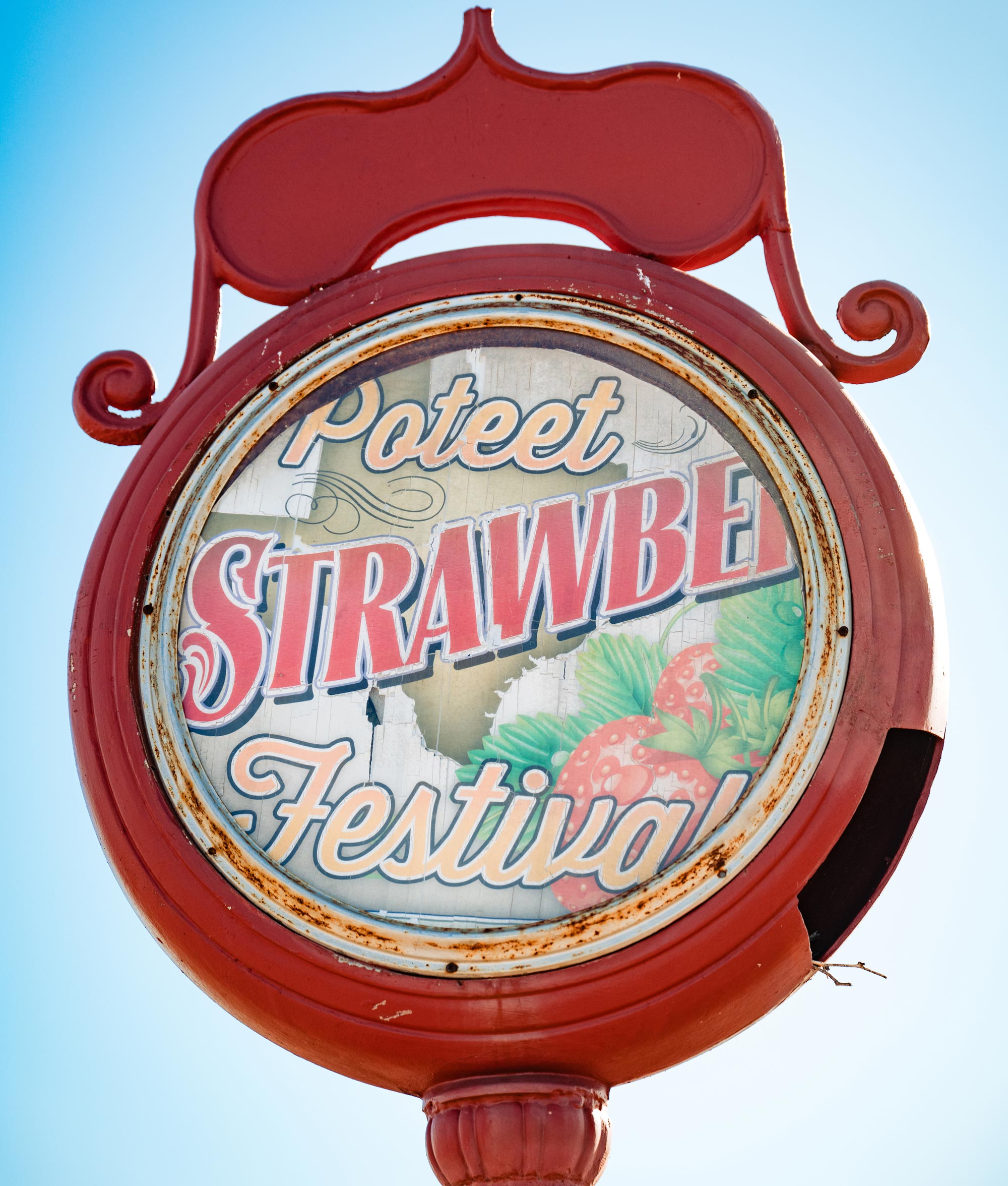 A red, circular sign that reads Poteet Strawberry Festival, with images of the state of Texas and strawberries behind it