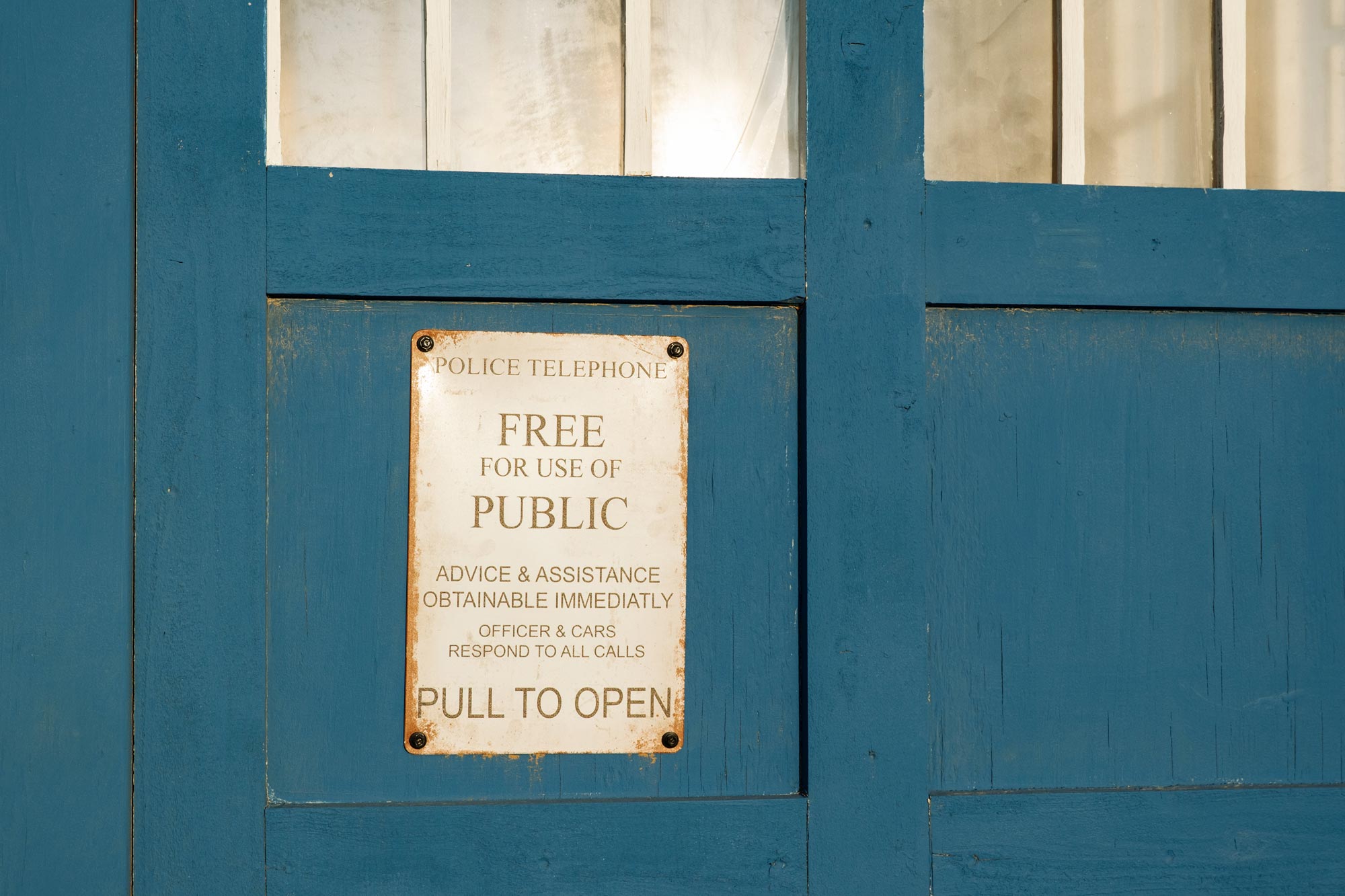 A blue door with the words "police telephone" and "free for use of public" on a sign