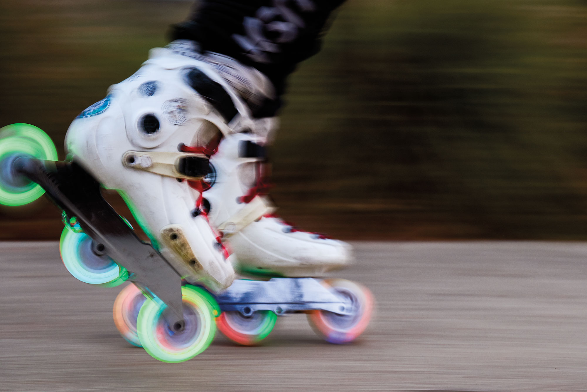 A close-up image of a person's feet as they rollerblade in white rollerblades with neon wheels