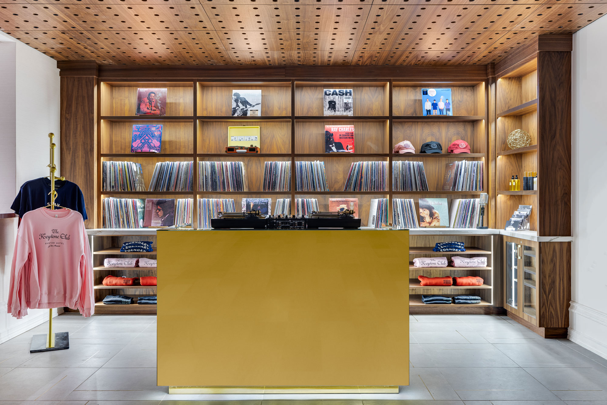 A room shelves filled with vinyl records and merchandise including crewneck sweatshirts.
