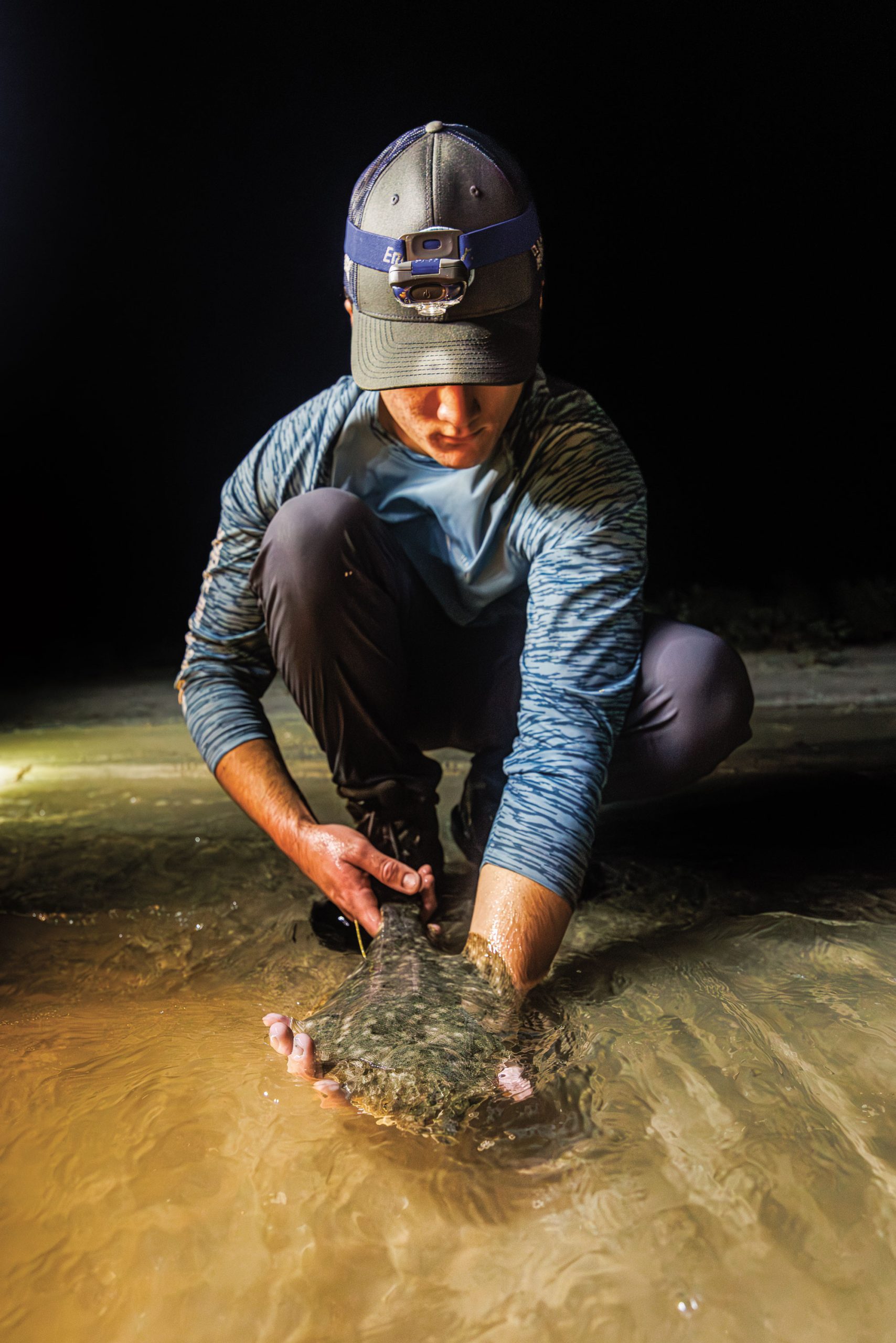 A man holds a flounder above water