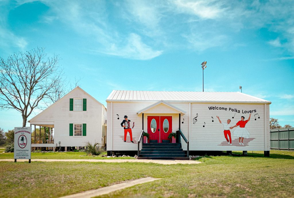 A white building with a red door and a mural with a man and woman dancing