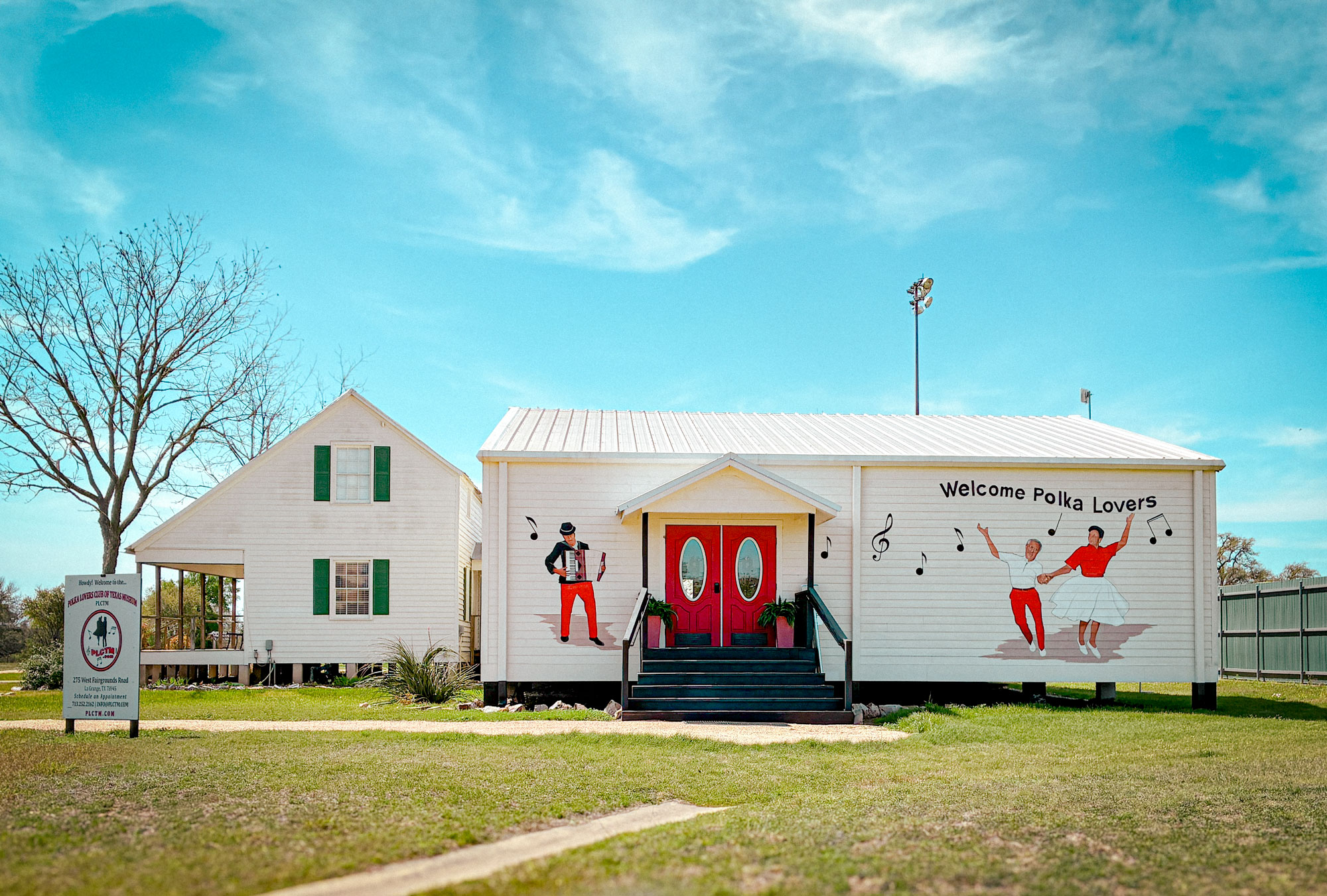 A white building with a red door and a mural with a man and woman dancing