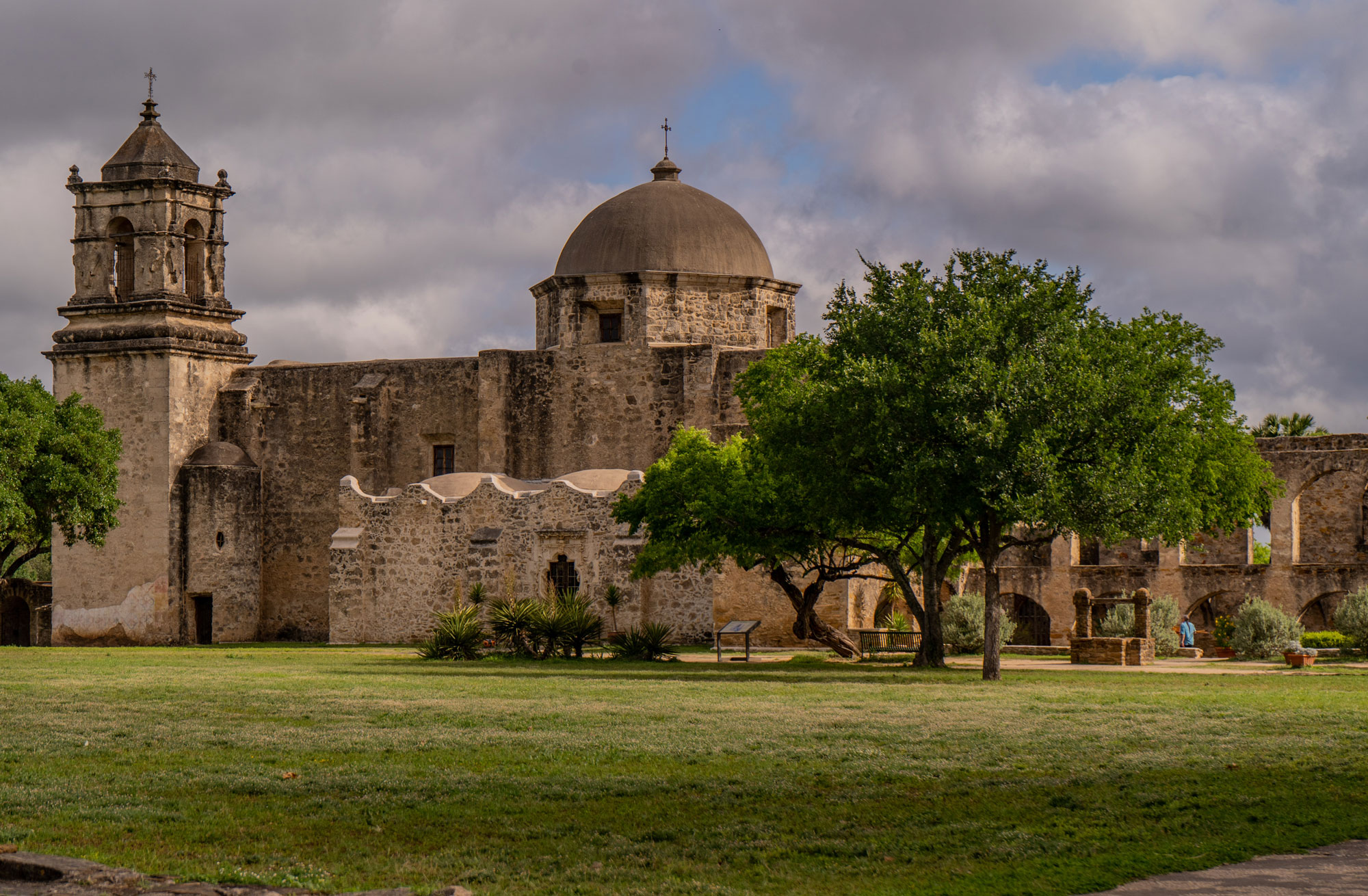 A large stone structure with a turret on the left and a dome on the right with three trees in front