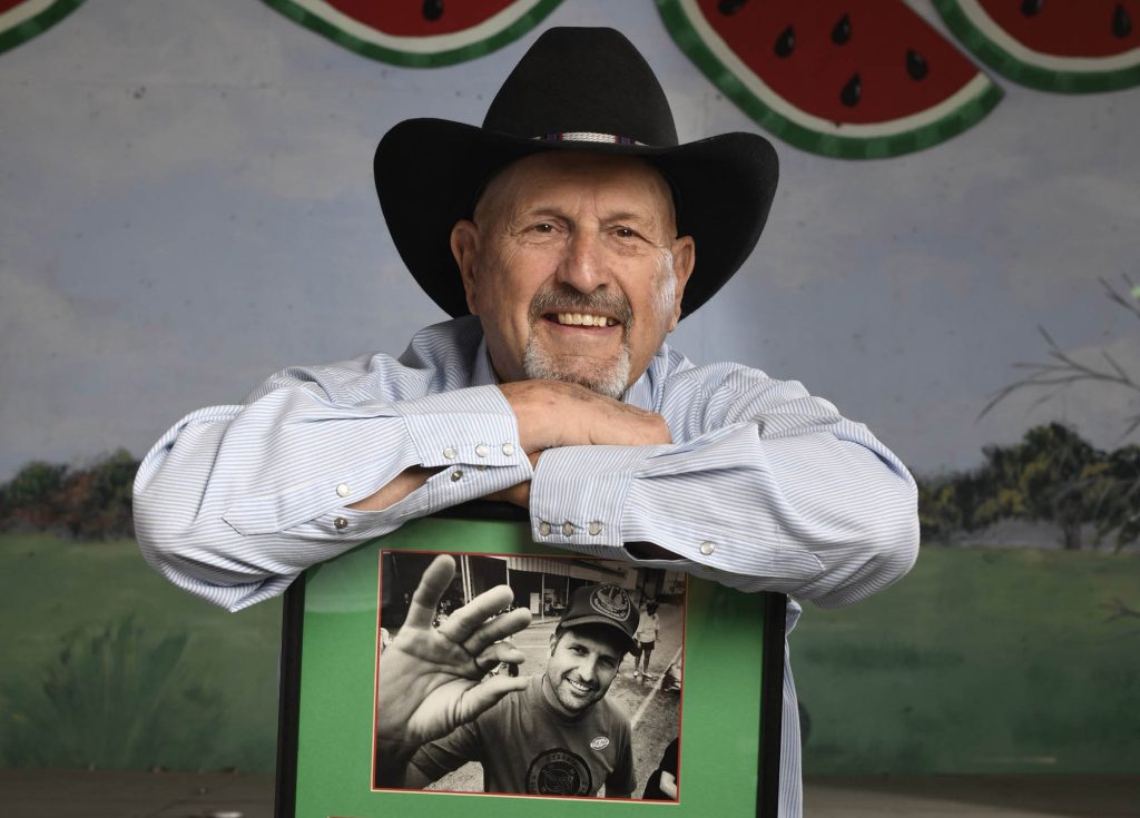 A man in a black cowboy hat leaning over a picture in a frame