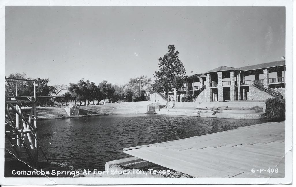 A pool surrounded by trees and a brick pool house