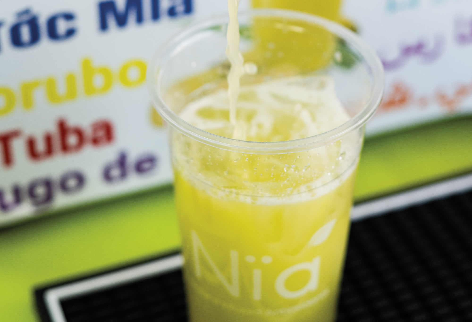 A plastic cup of yellow-green juice with ice in it