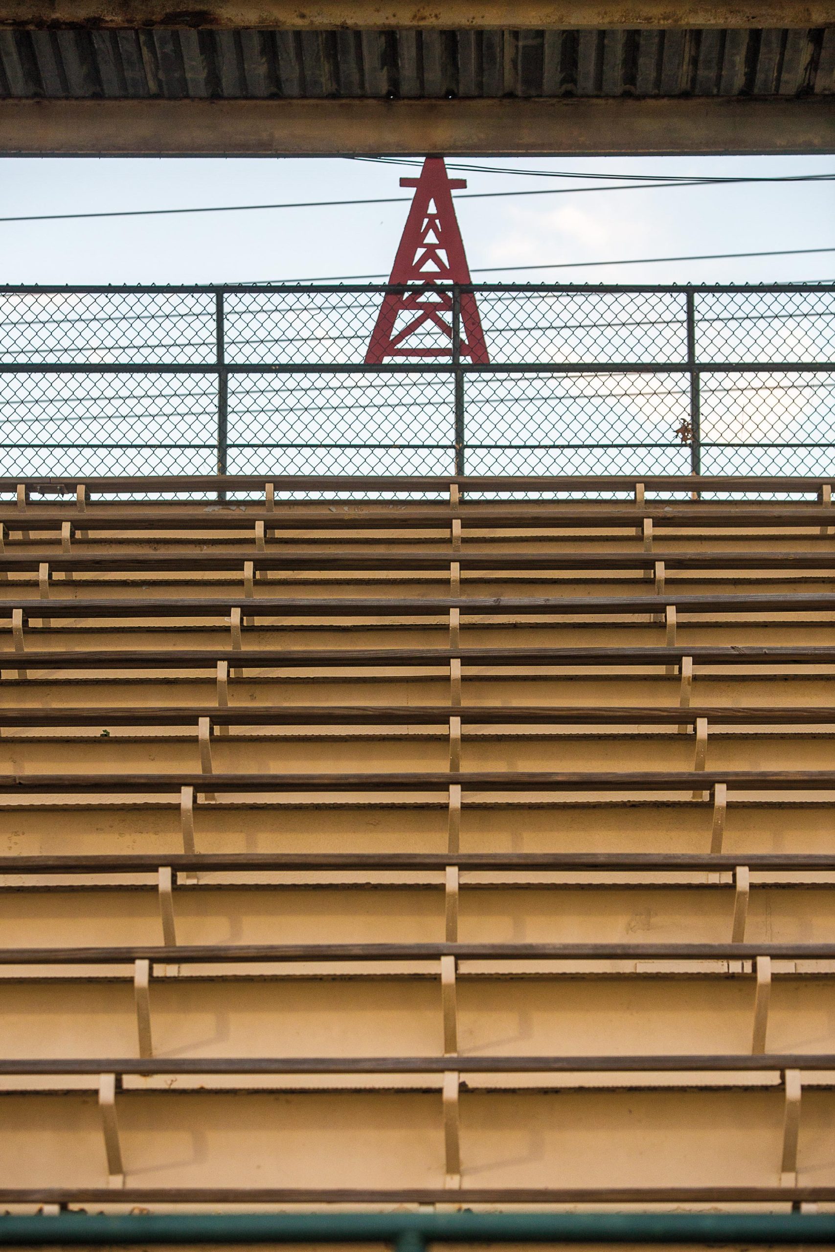 Empty bleachers at a baseball stadium with a red oil derrick logo near the top