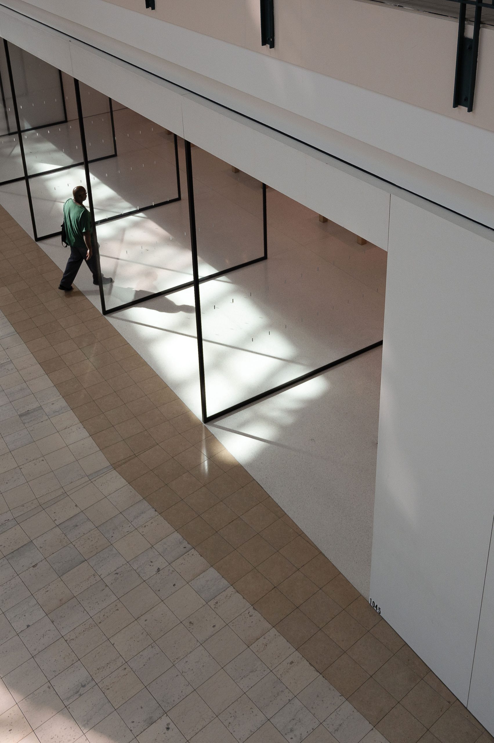 A person in a green shirt walking into the entrance of a mall