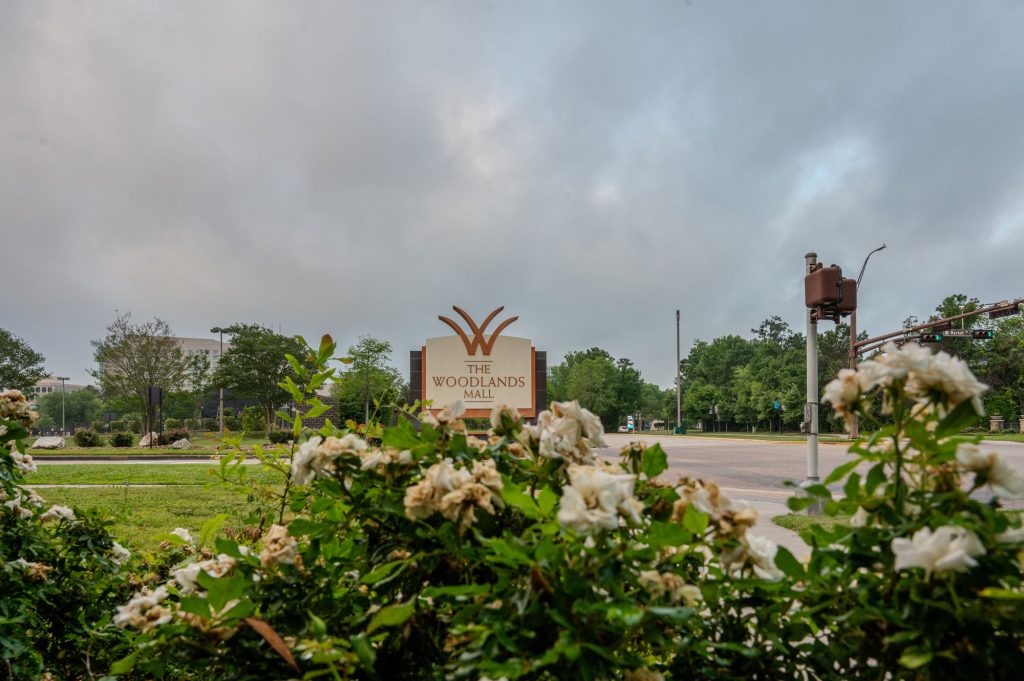 A sign for the Woodlands Mall under a cloudy sky