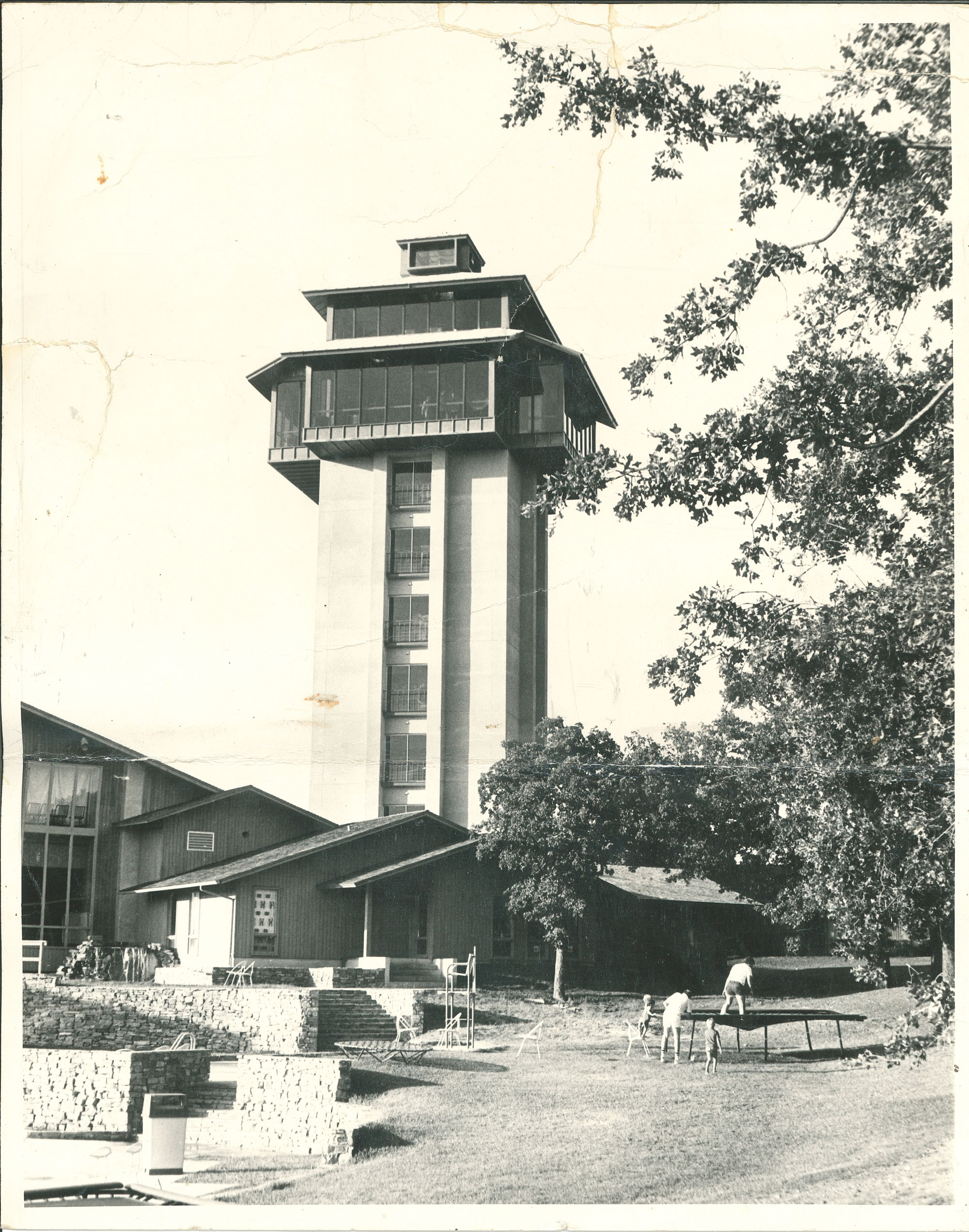 A large tower with people playing in the yard in front of it