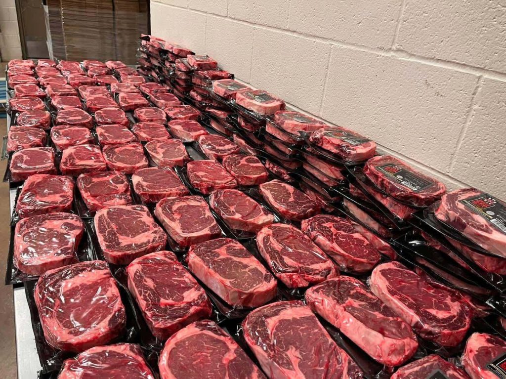 Dozens of steaks wrapped in plastic on a table