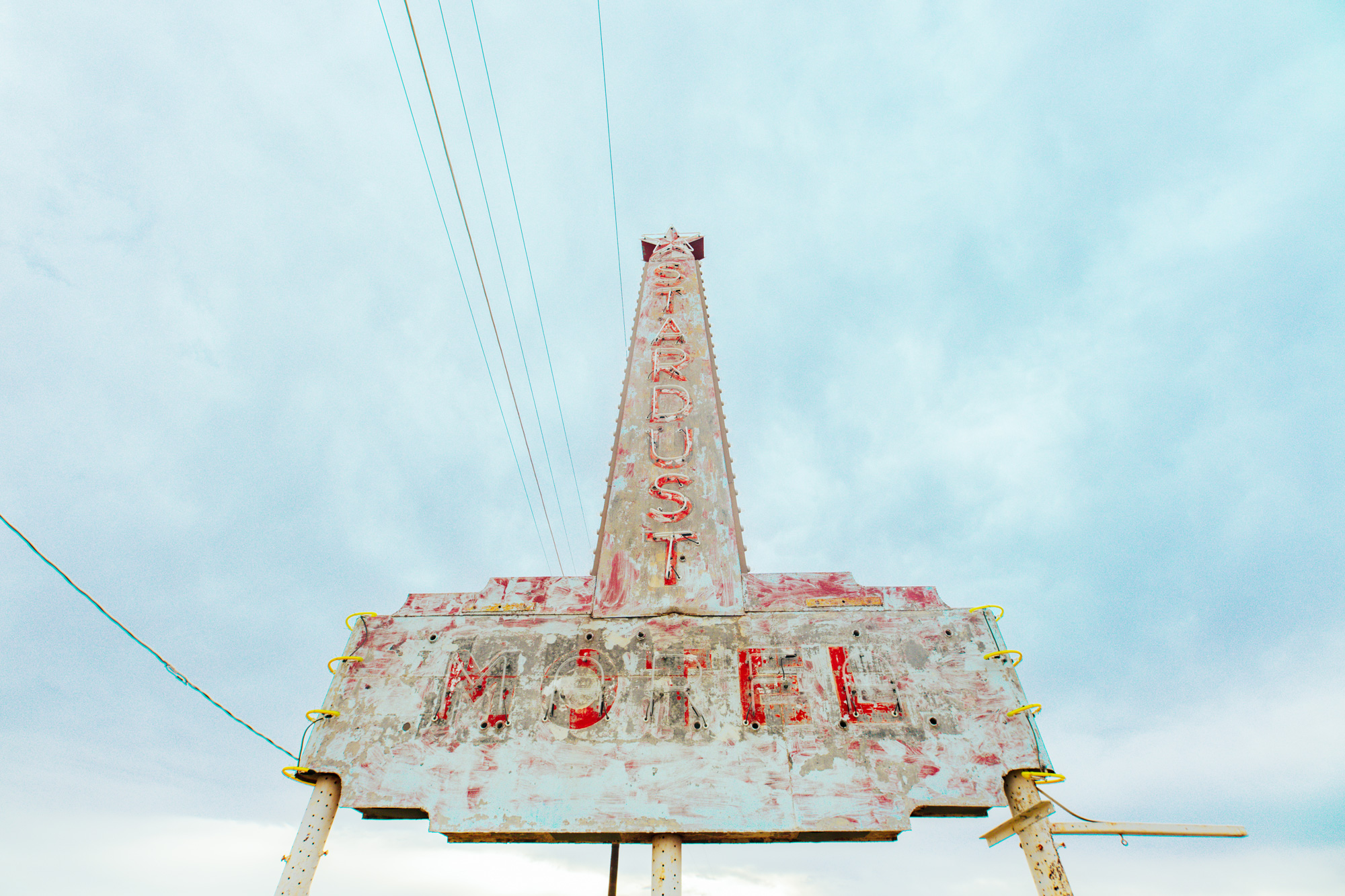 A faded blue sign with a star on top that reads Stardust Motel