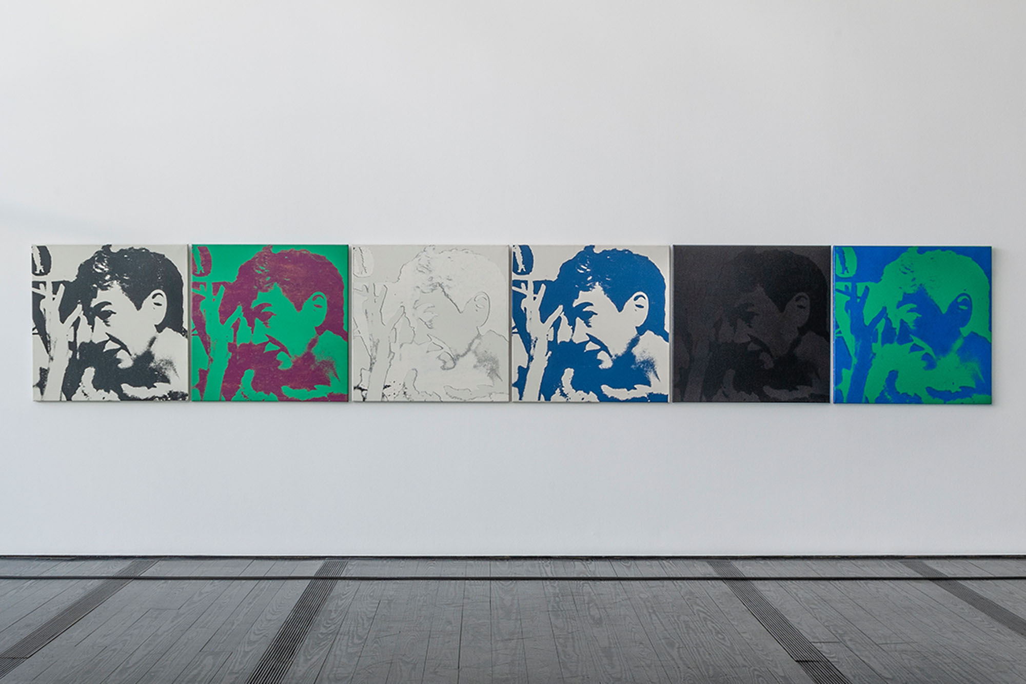 A multicolored (white/grey, green/purple, white, white/blue, black, blue/green) series of five silkscreen paintings, portraying the same image of a woman holding a cigarette, hung on a white wall of the Menil Collection.