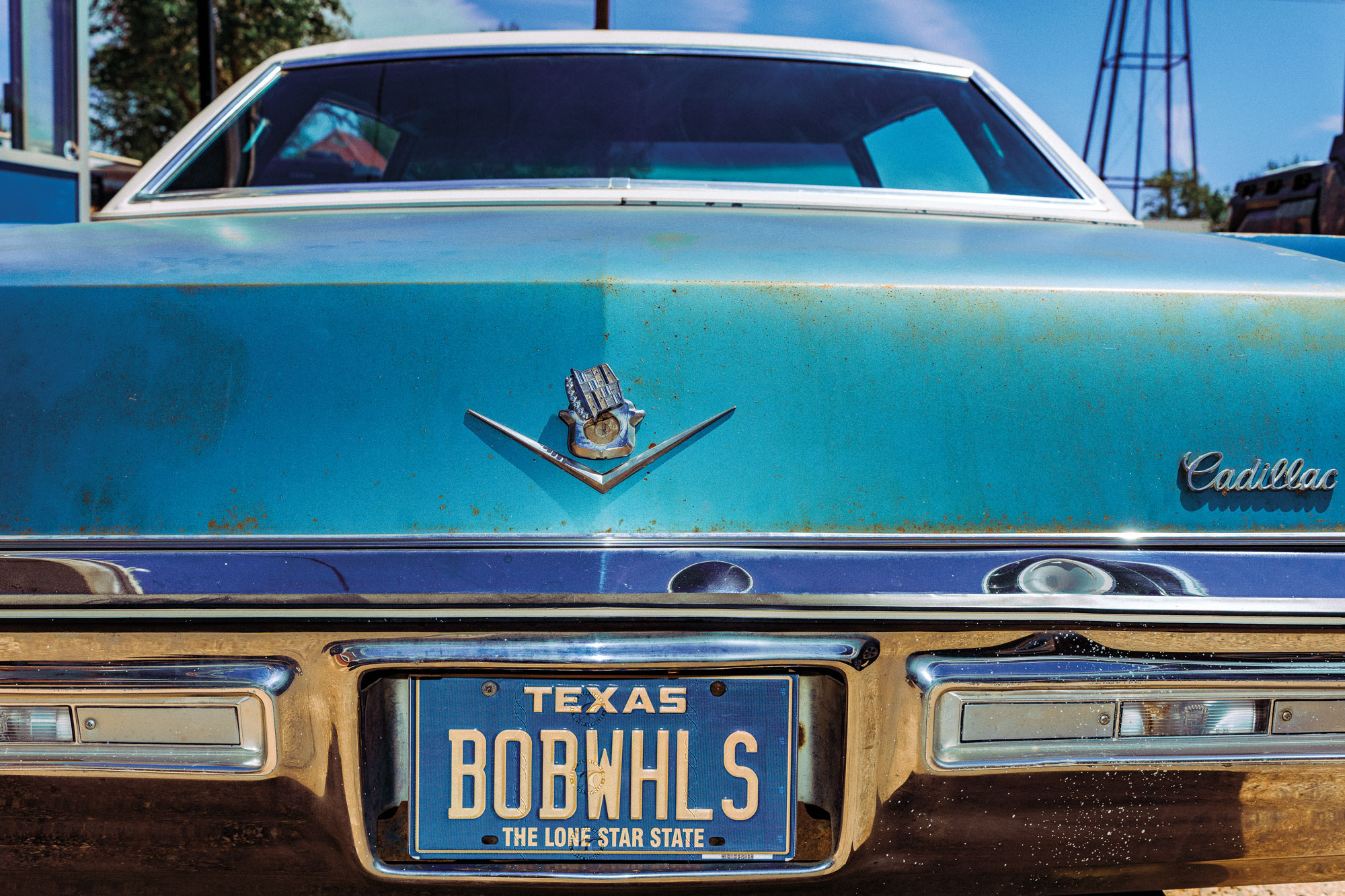 The back of a vintage blue cadillac with a license plate that reads "BOBWHLS"