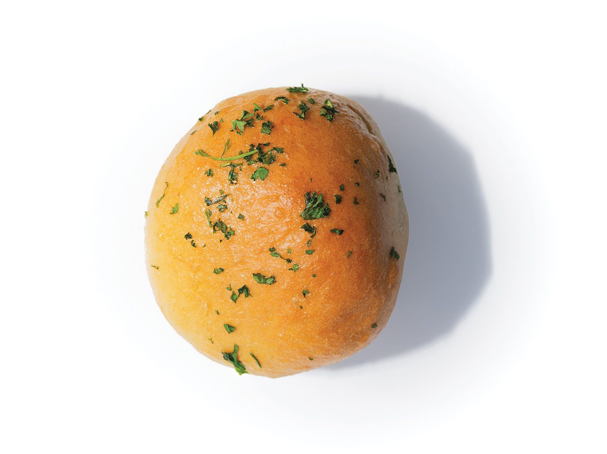 A spherical kolache lightly sprinkled with a green, leafy garnish.