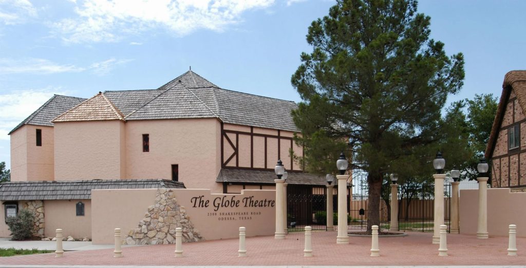 A tan building with dark wood accents and a slanted shingle roof with a sign in front of it that reads "The Globe Theatre"