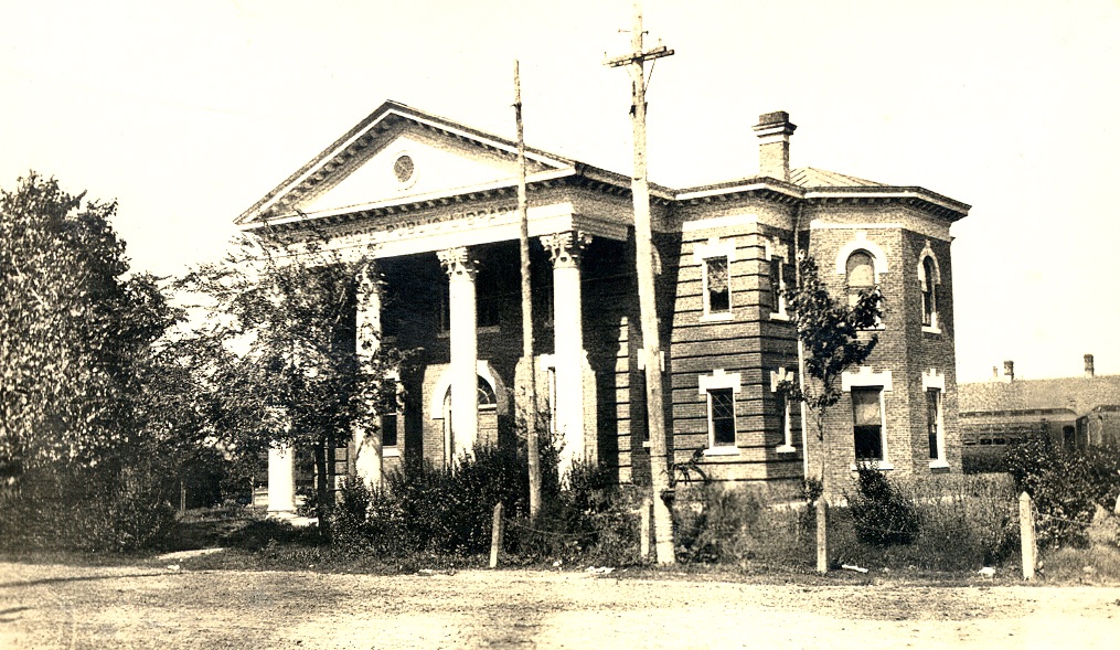 Black and white photo of Bryan's Carnegie History Center, built in a field with electrical poles in front.