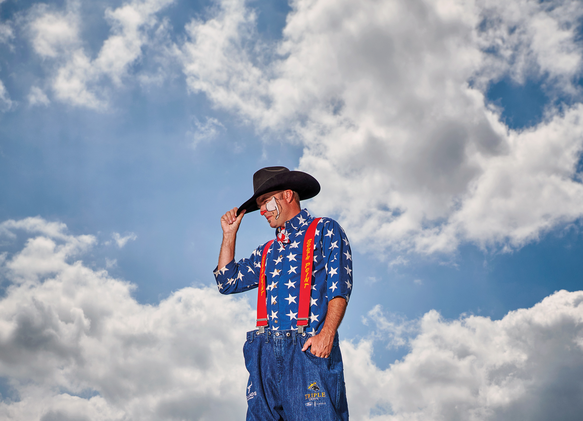 A man dressed as a rodeo clown wearing a cowboy hat and face paint