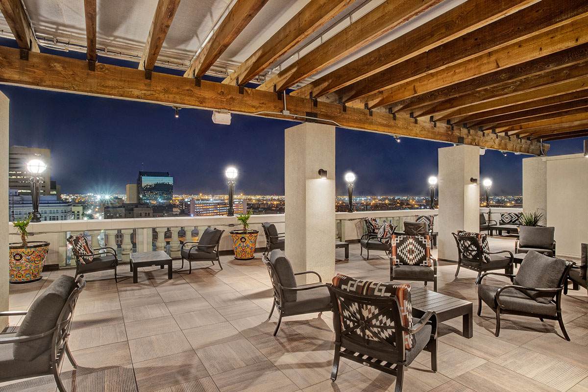 A covered deck with chairs collected in groups overlooks the night sky