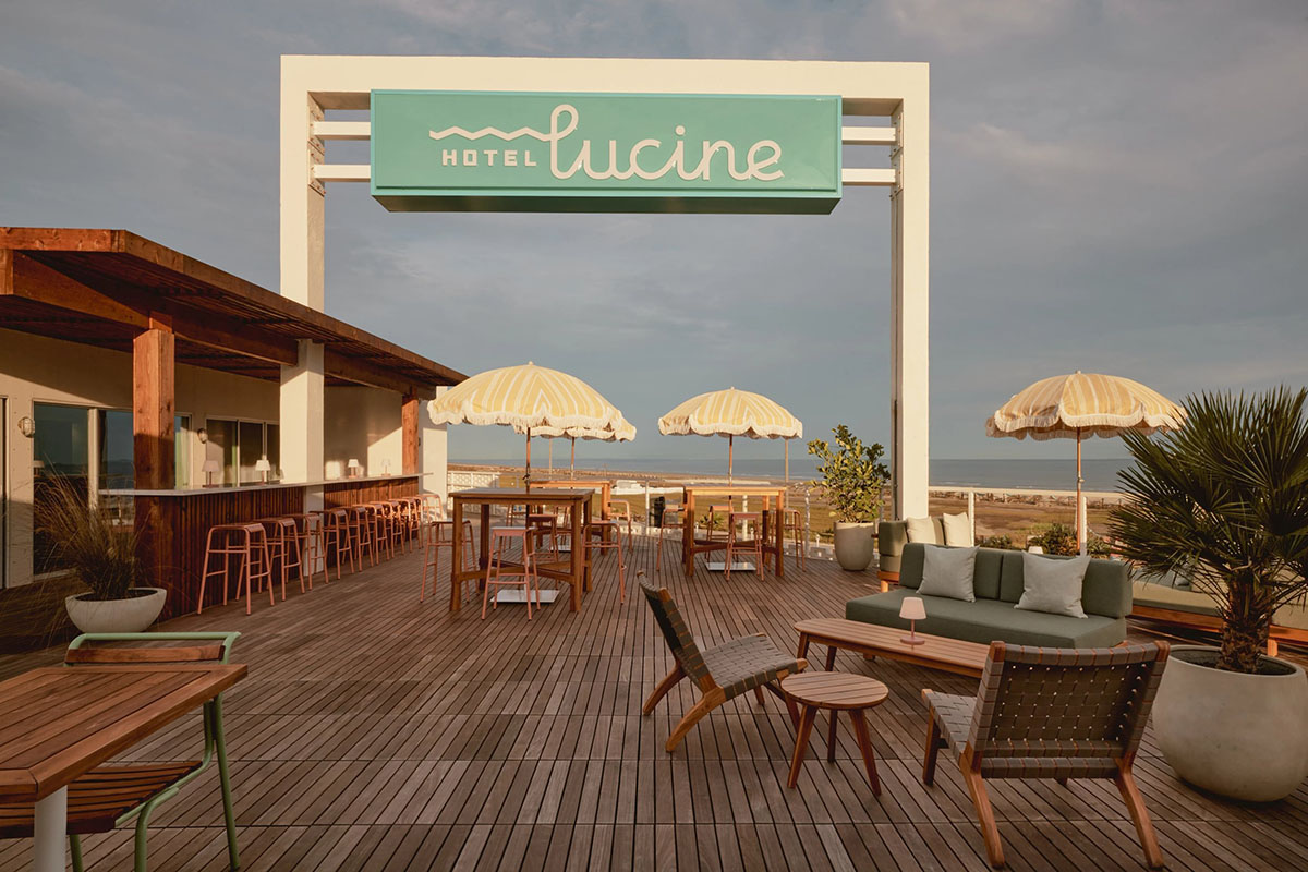 A permanent banner labeled "hotel Lucine" is lofted above a deck dotted with umbrellas and tables