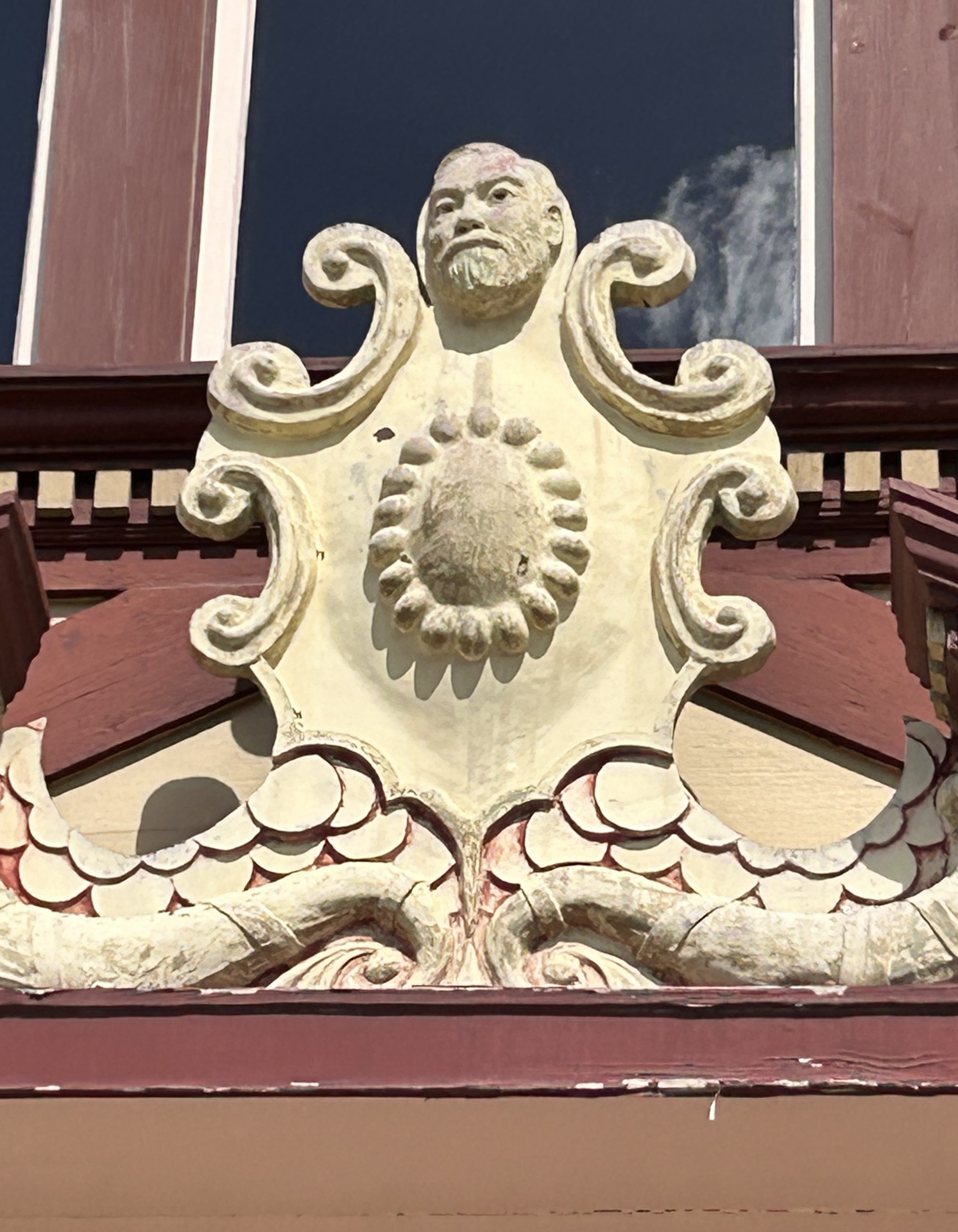 Close-up photo of exterior plaster adornment with Carnegie's head appearing at top of it.