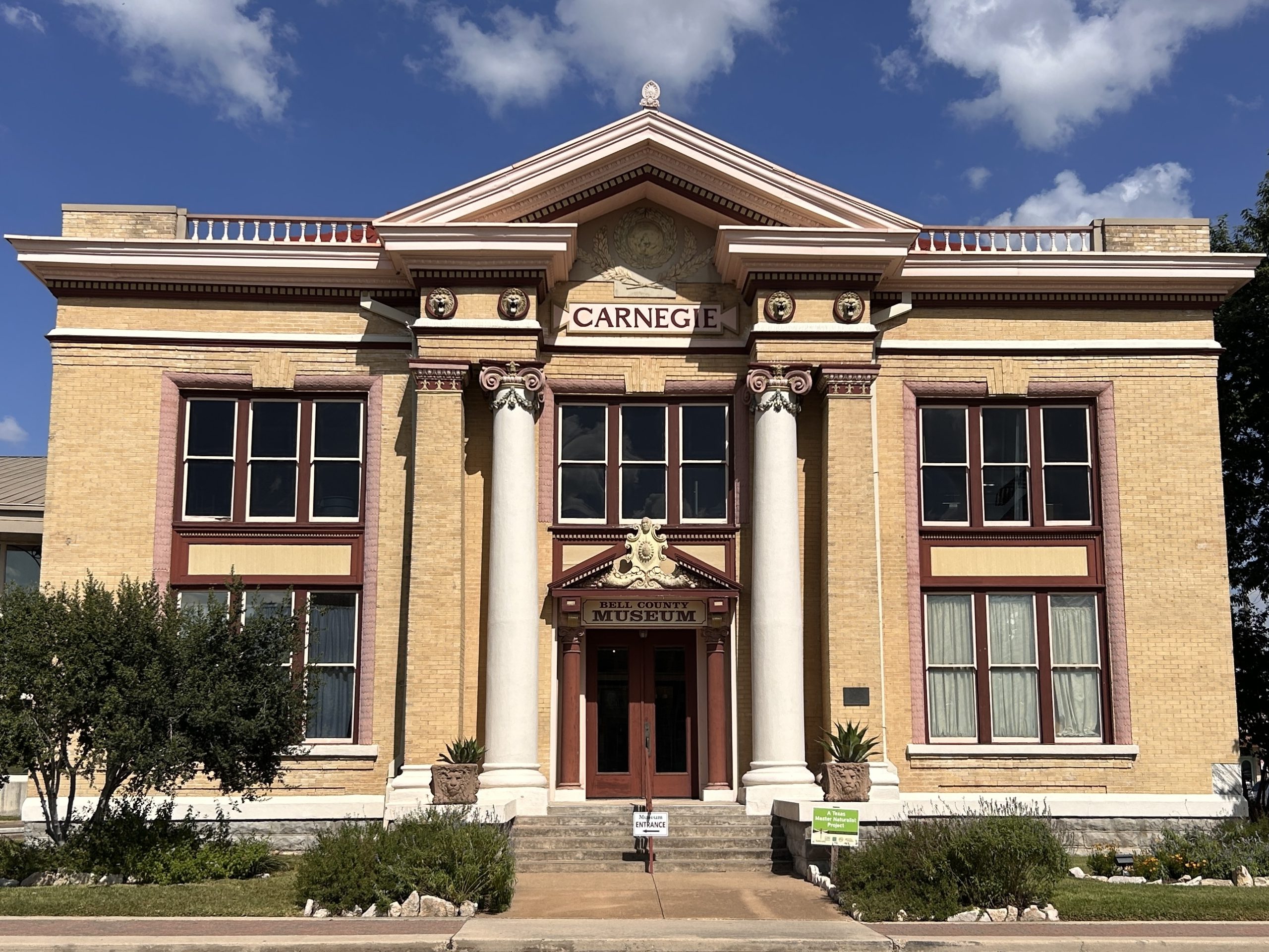 Exterior of Bell County Museum's beaux art-style building with two stories, beige bricks, and two columns.
