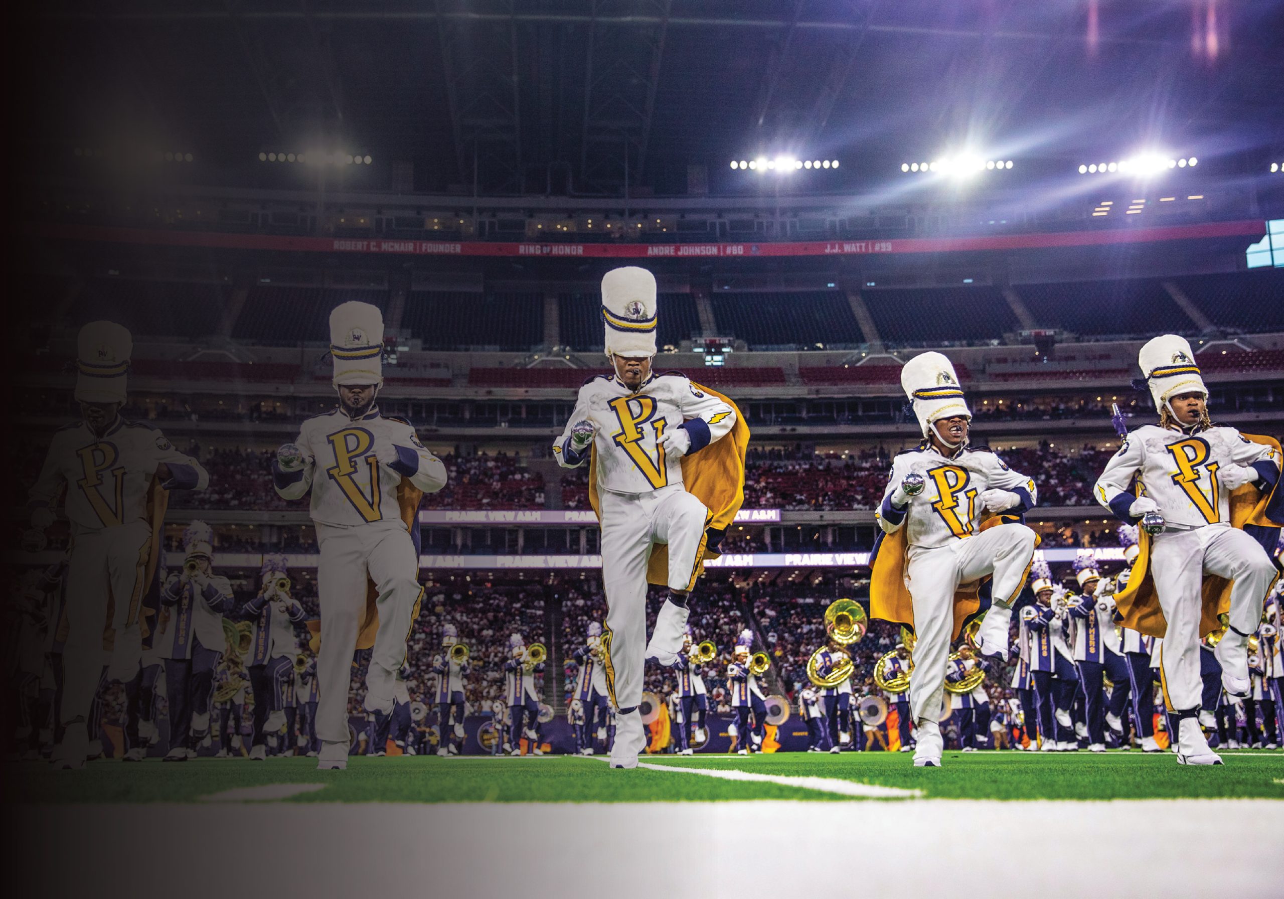 A marching band wearing white and purple uniforms on a football field in a large stadium